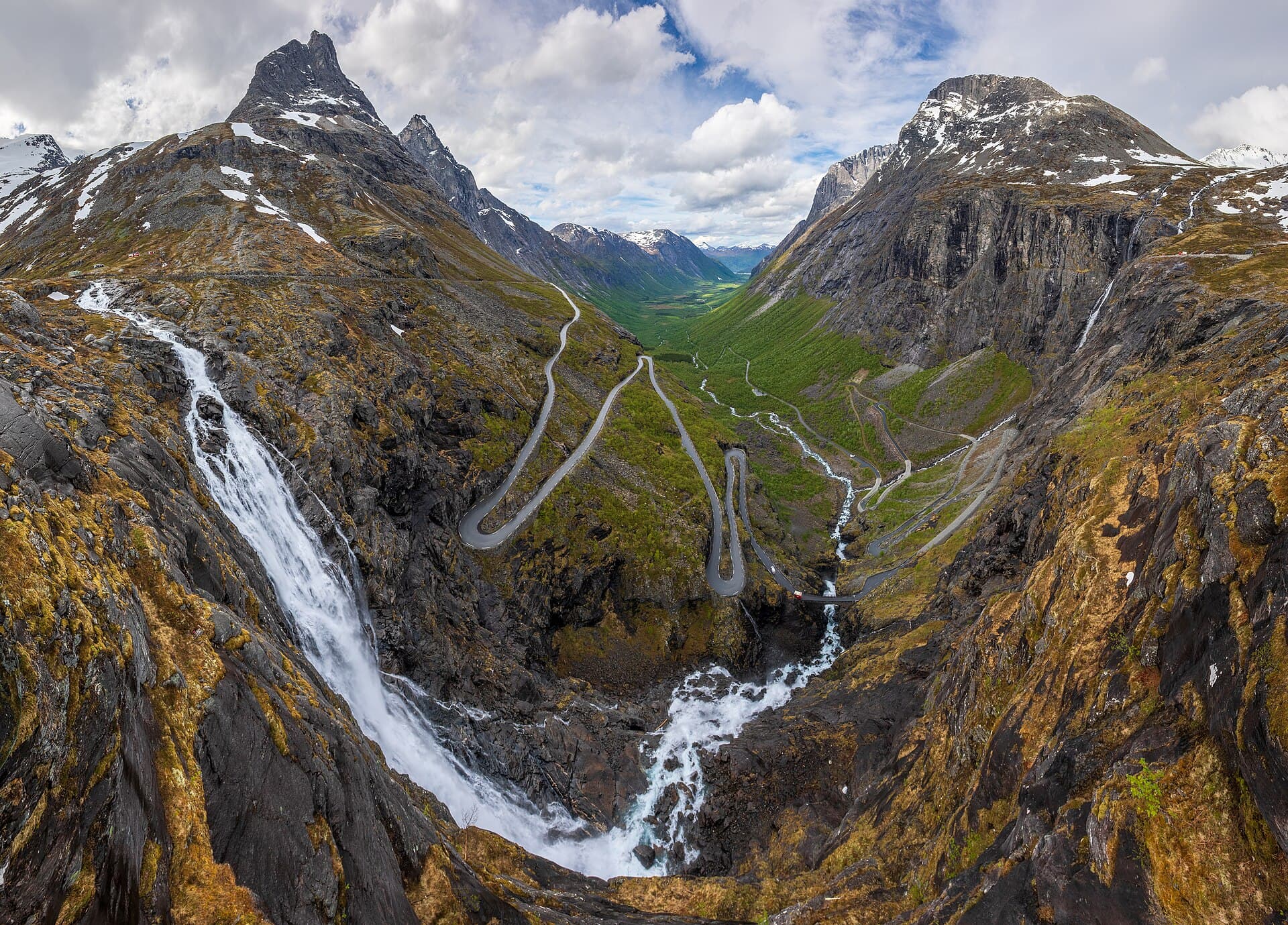 Hairpin bends climbing the mountain wall beneath Stigfossen waterfall on Trollstigen.