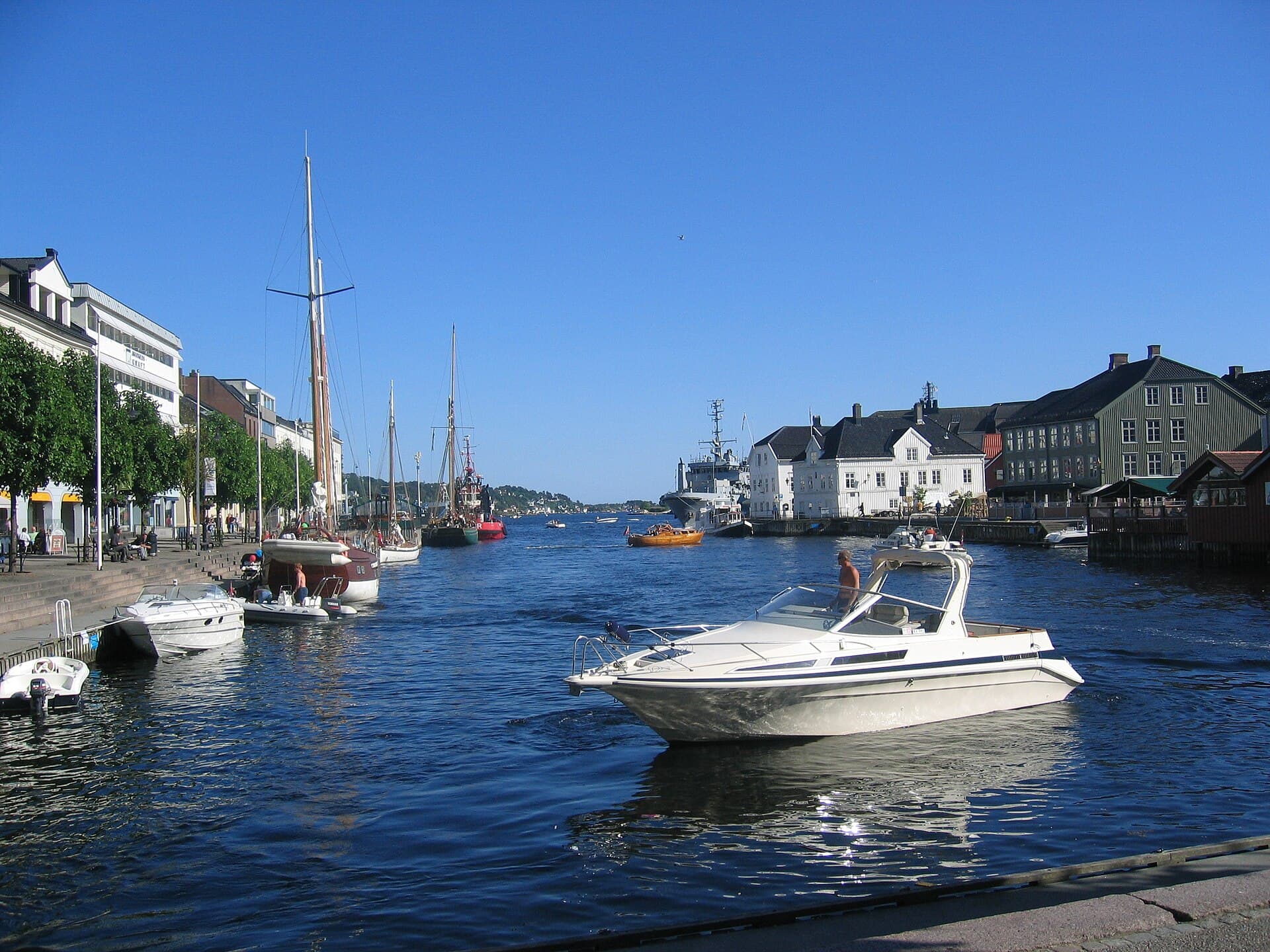 Historic timber merchant houses and boats surrounding the inner harbour of Pollen in Arendal.