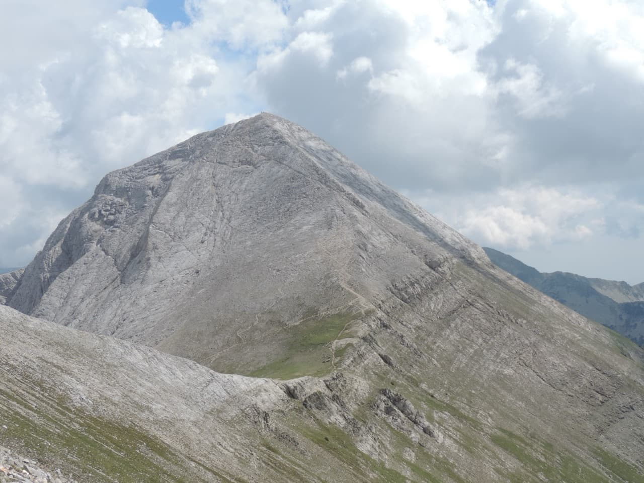 The jagged white marble pyramid of Mount Vihren towering over alpine meadows in Pirin National Park above Bansko
