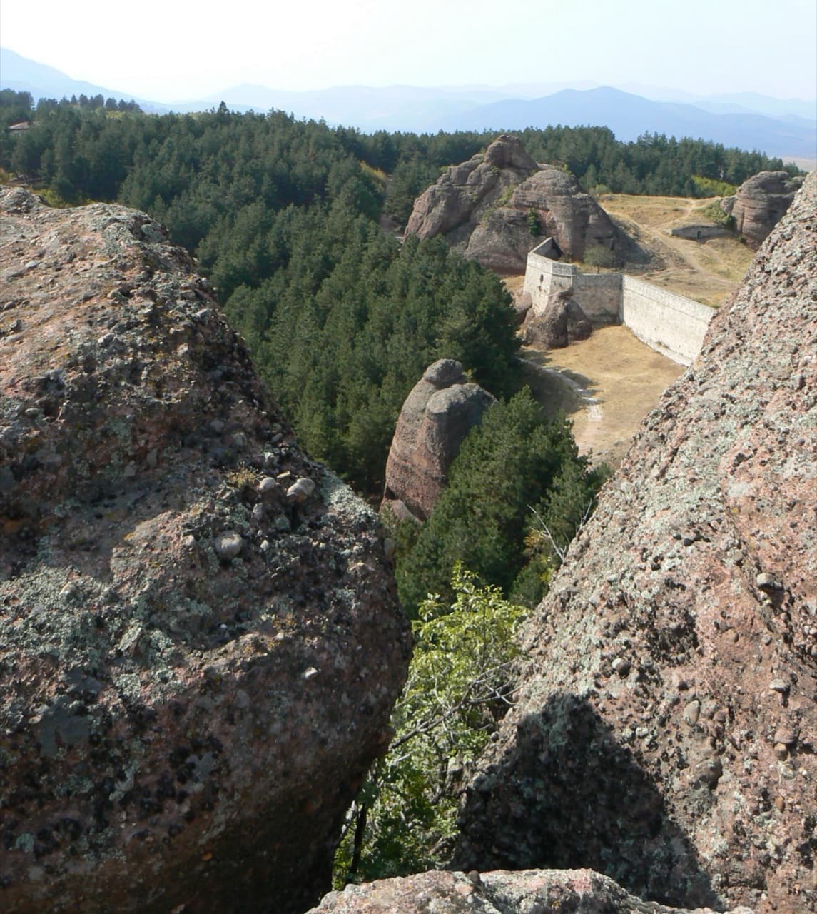 The ancient stone walls of Kaleto Fortress integrated into towering red sandstone pinnacles in Belogradchik