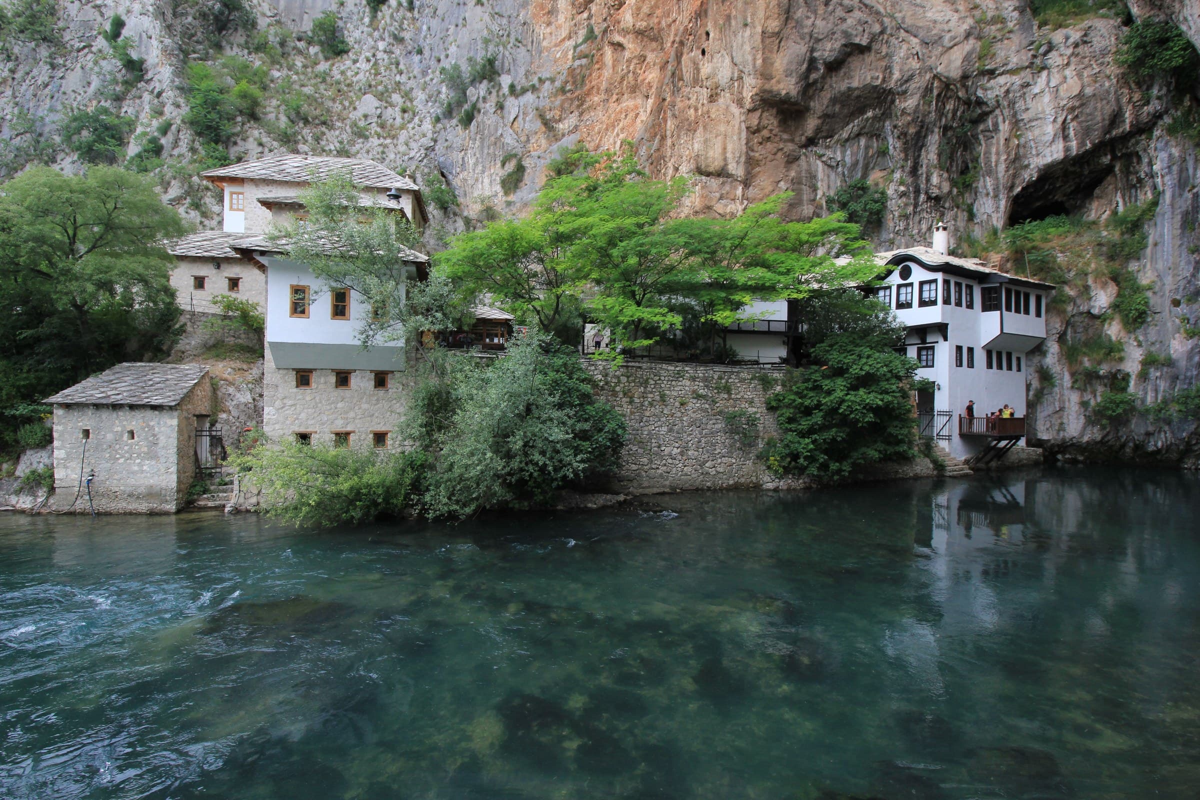 Whitewashed Ottoman Blagaj Tekke dervish monastery built beside the turquoise Buna River karst spring cliff