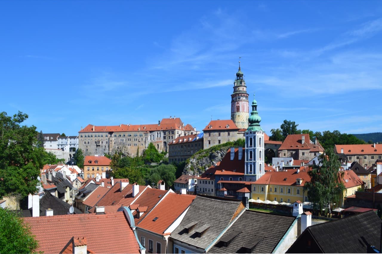 The pastel Renaissance castle tower rising above the red-tiled roofs and looping Vltava River in Český Krumlov