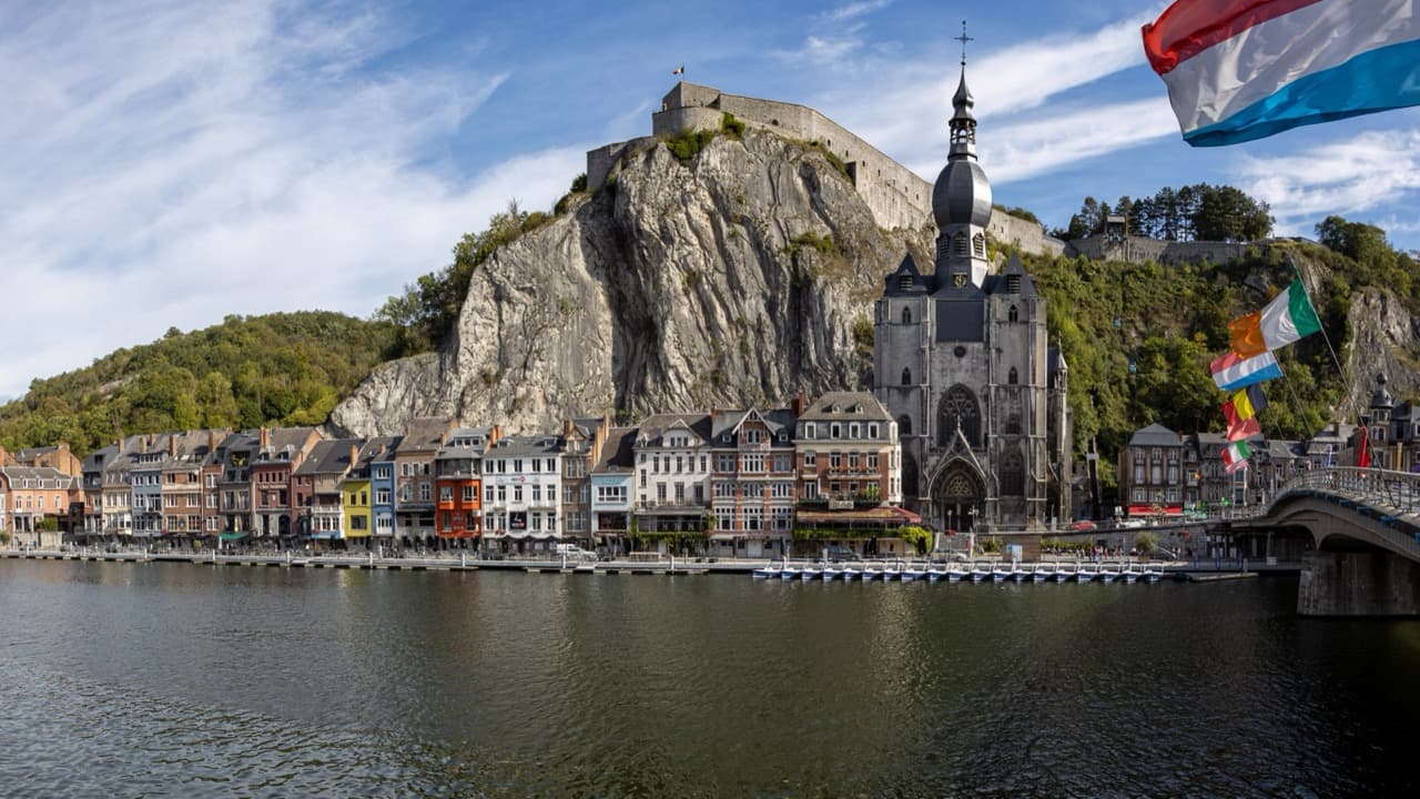 The cliffside Citadel and onion-domed Collegiate Church of Our Lady reflected in the Meuse River in Dinant