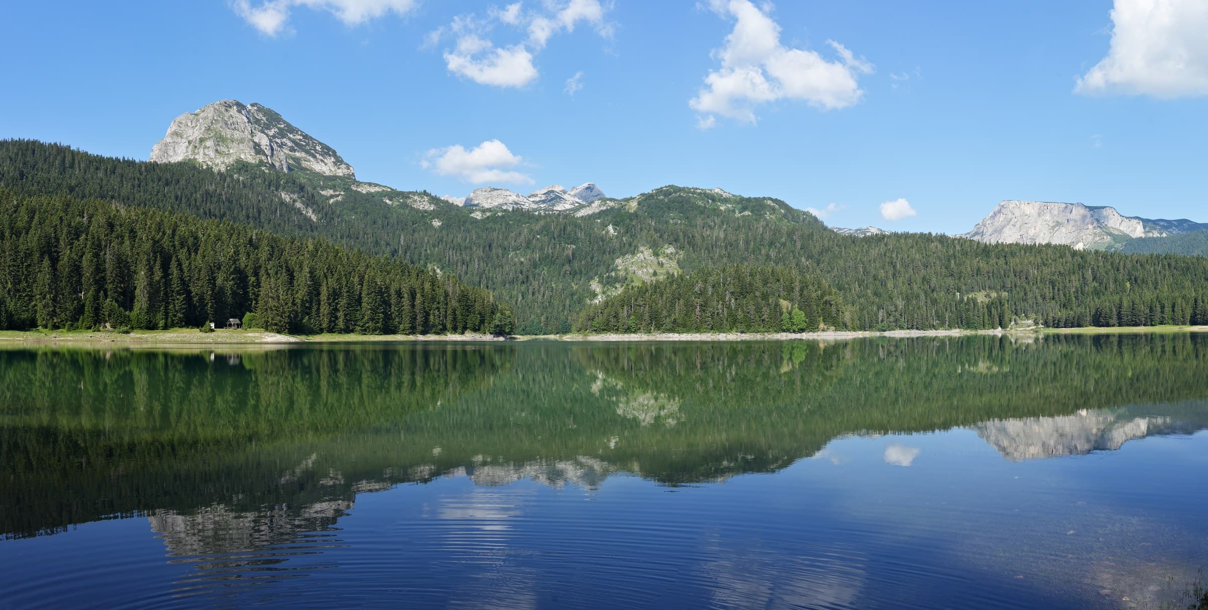 Mirrored alpine waters of Black Lake (Crno Jezero) framed by dark pine forests in Durmitor National Park