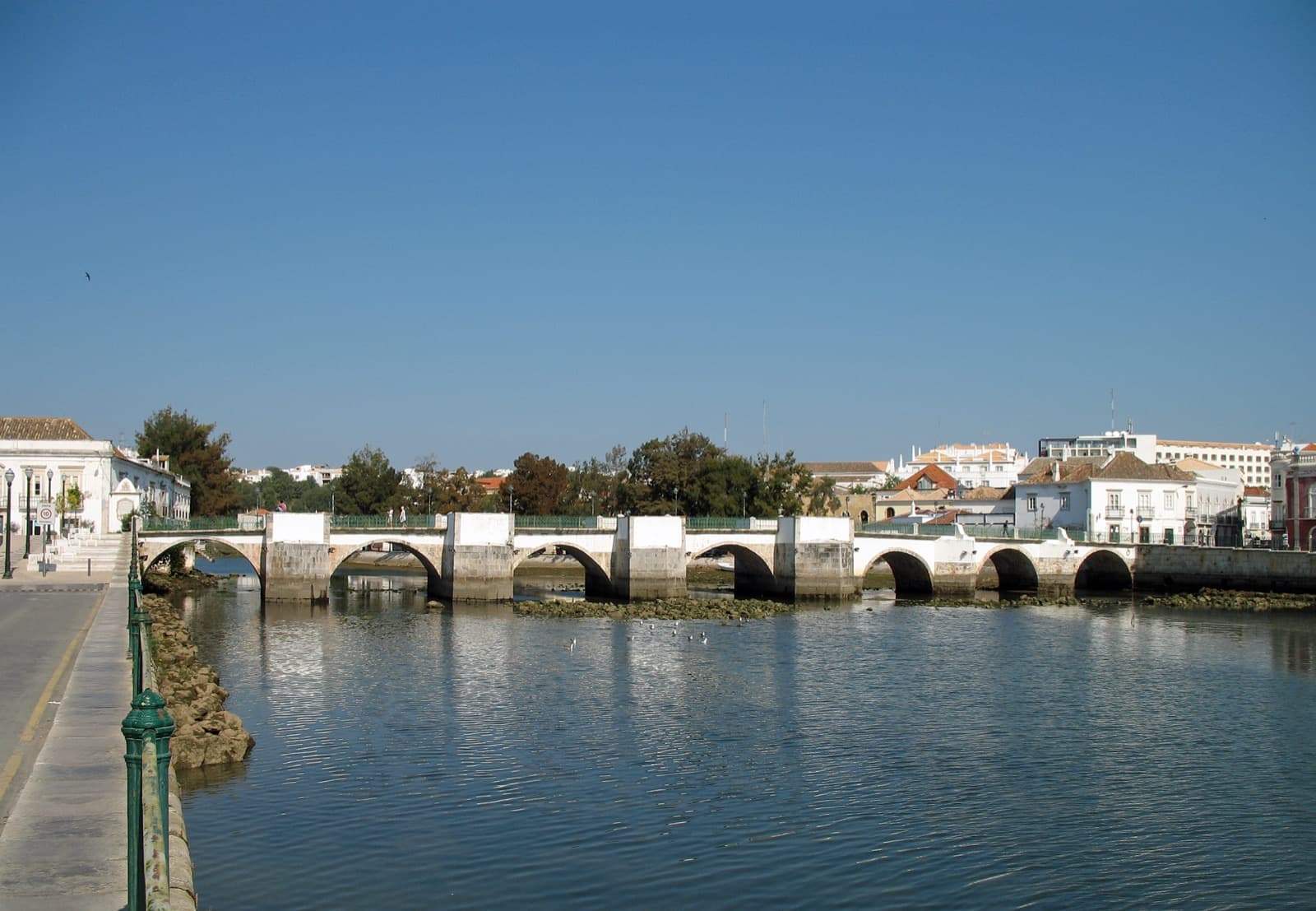 Historic Roman bridge and whitewashed buildings reflected in the Gilão river in Tavira