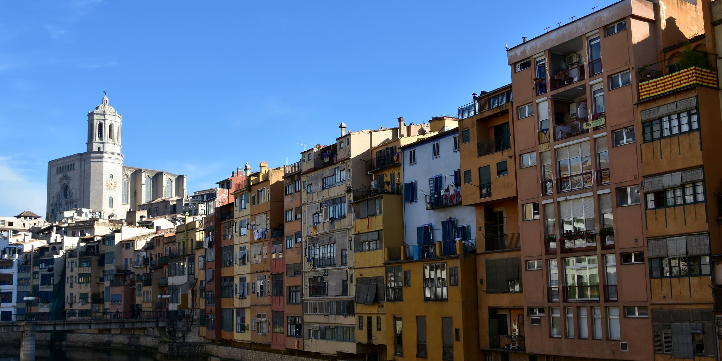 Painted houses along the River Onyar in Girona with the cathedral tower behind