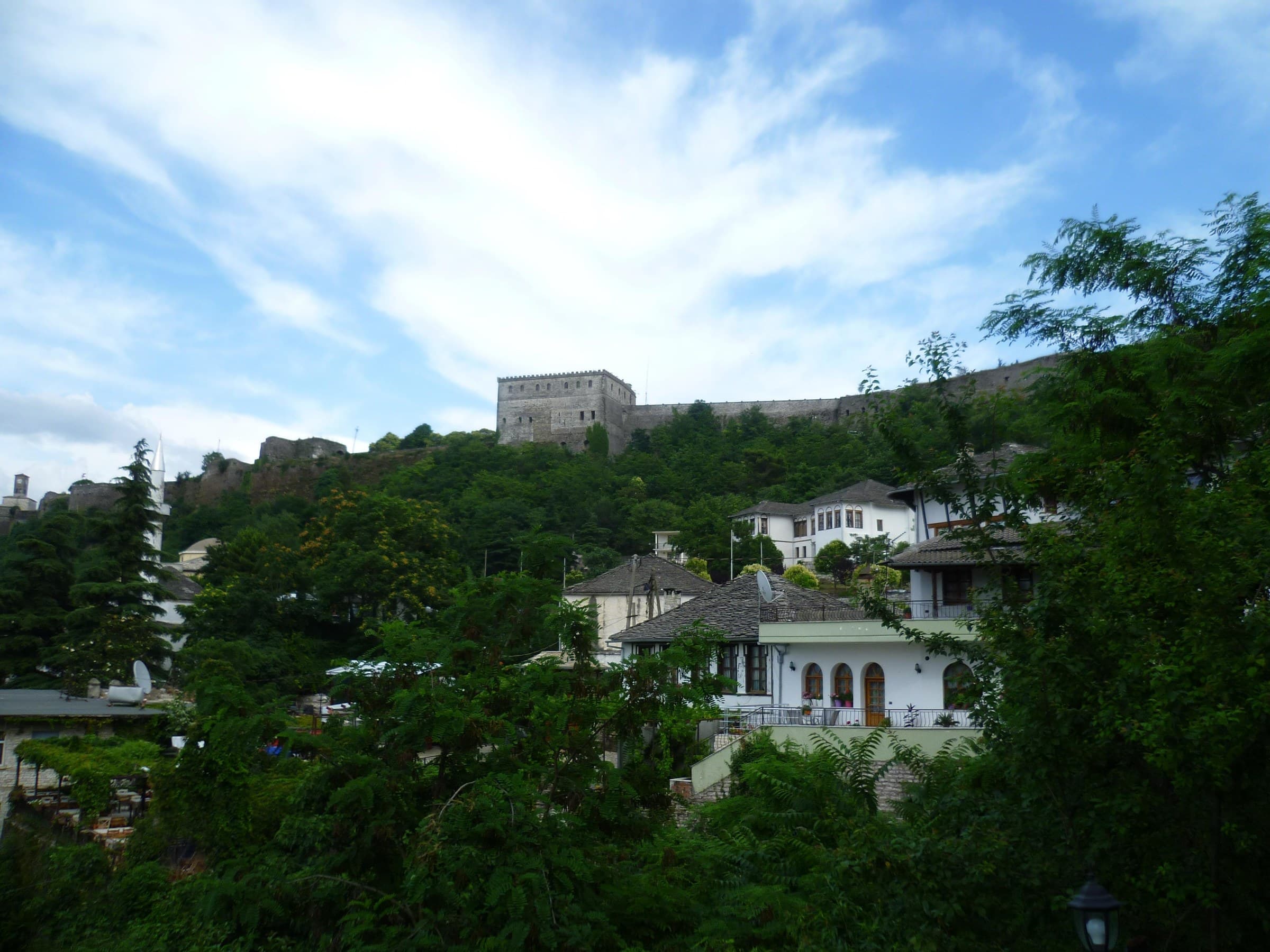 Massive stone castle walls of Gjirokastër Fortress overlooking the slate roofs of the historic town