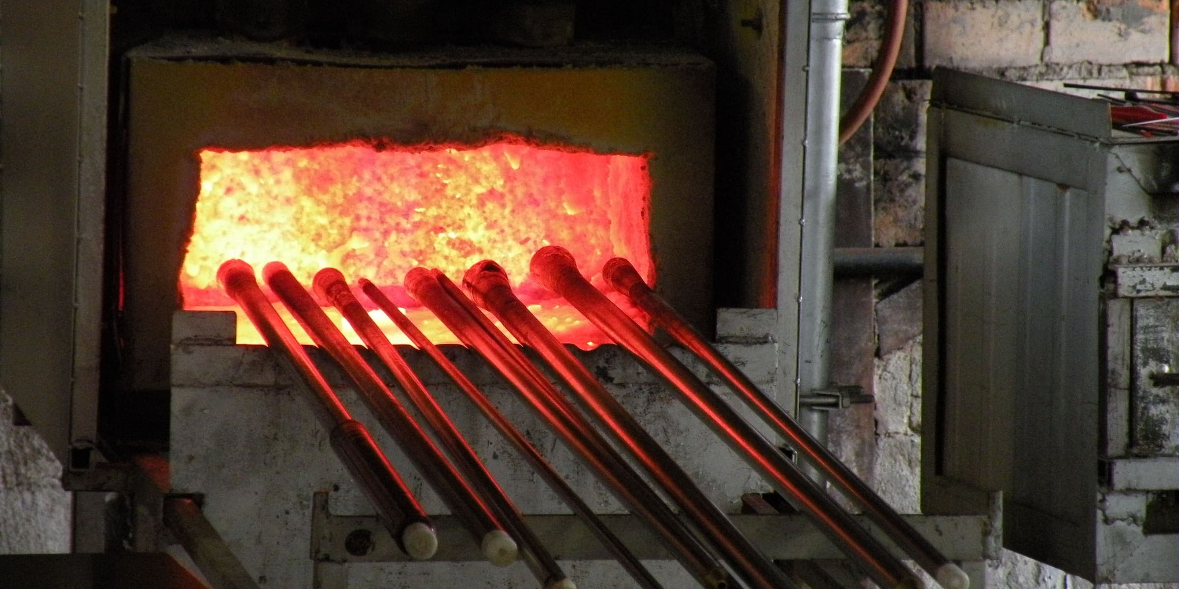 Blowpipes heating at the glowing furnace of the Bergdala glassworks