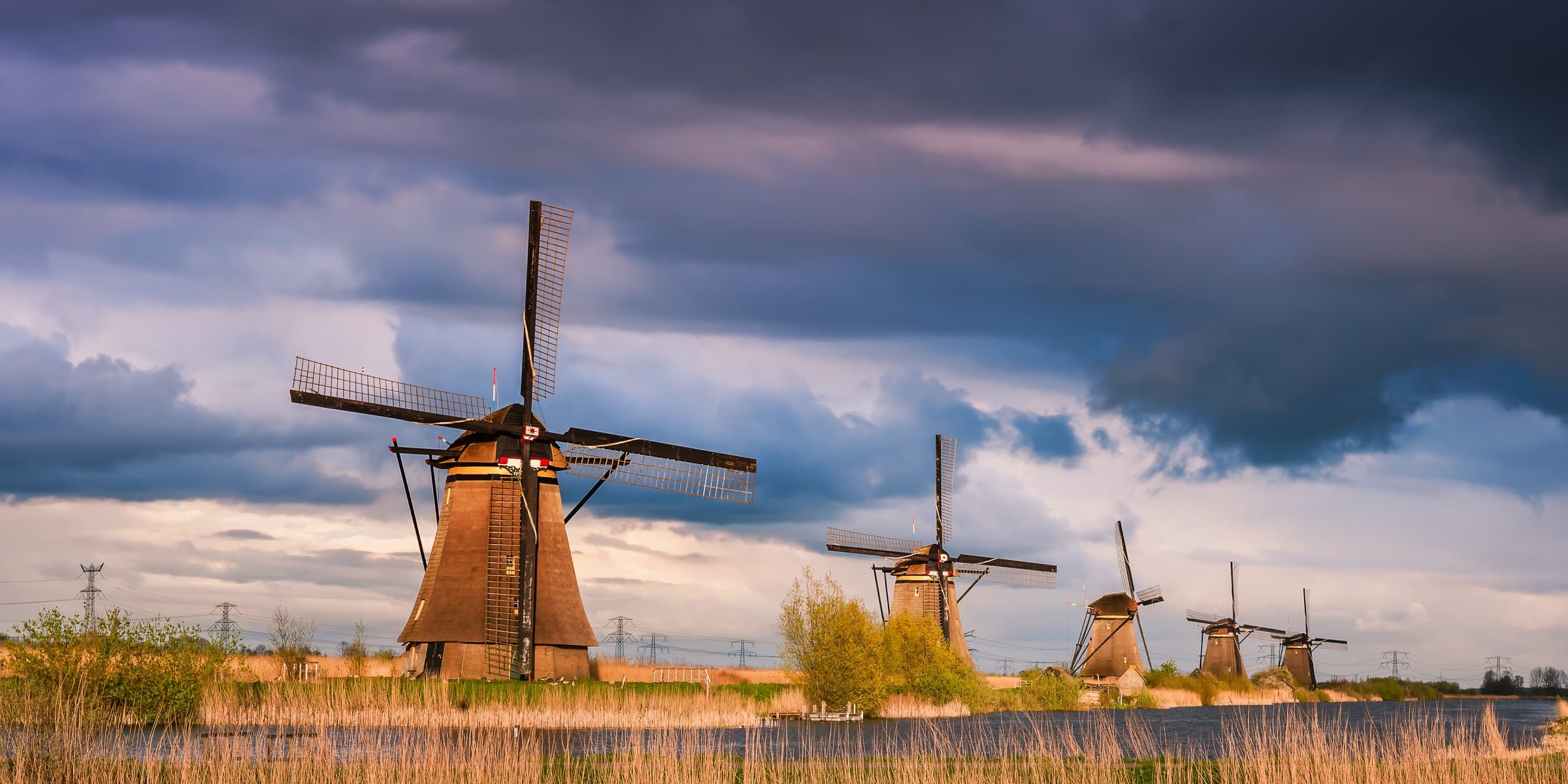 Historic Kinderdijk drainage windmills lined along the water at evening sunset