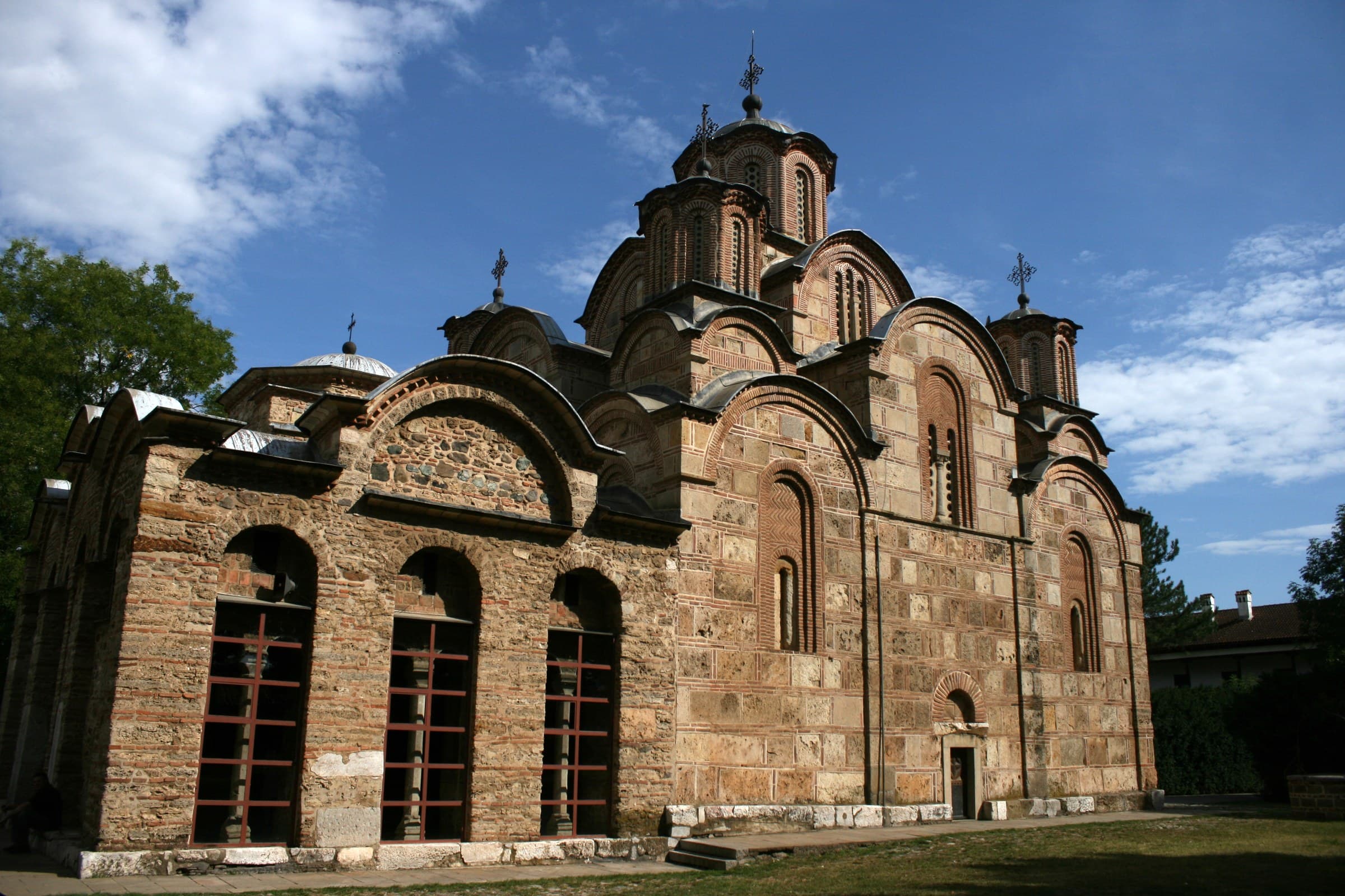 The five domes and striped brickwork of Gračanica monastery church rising above its walls