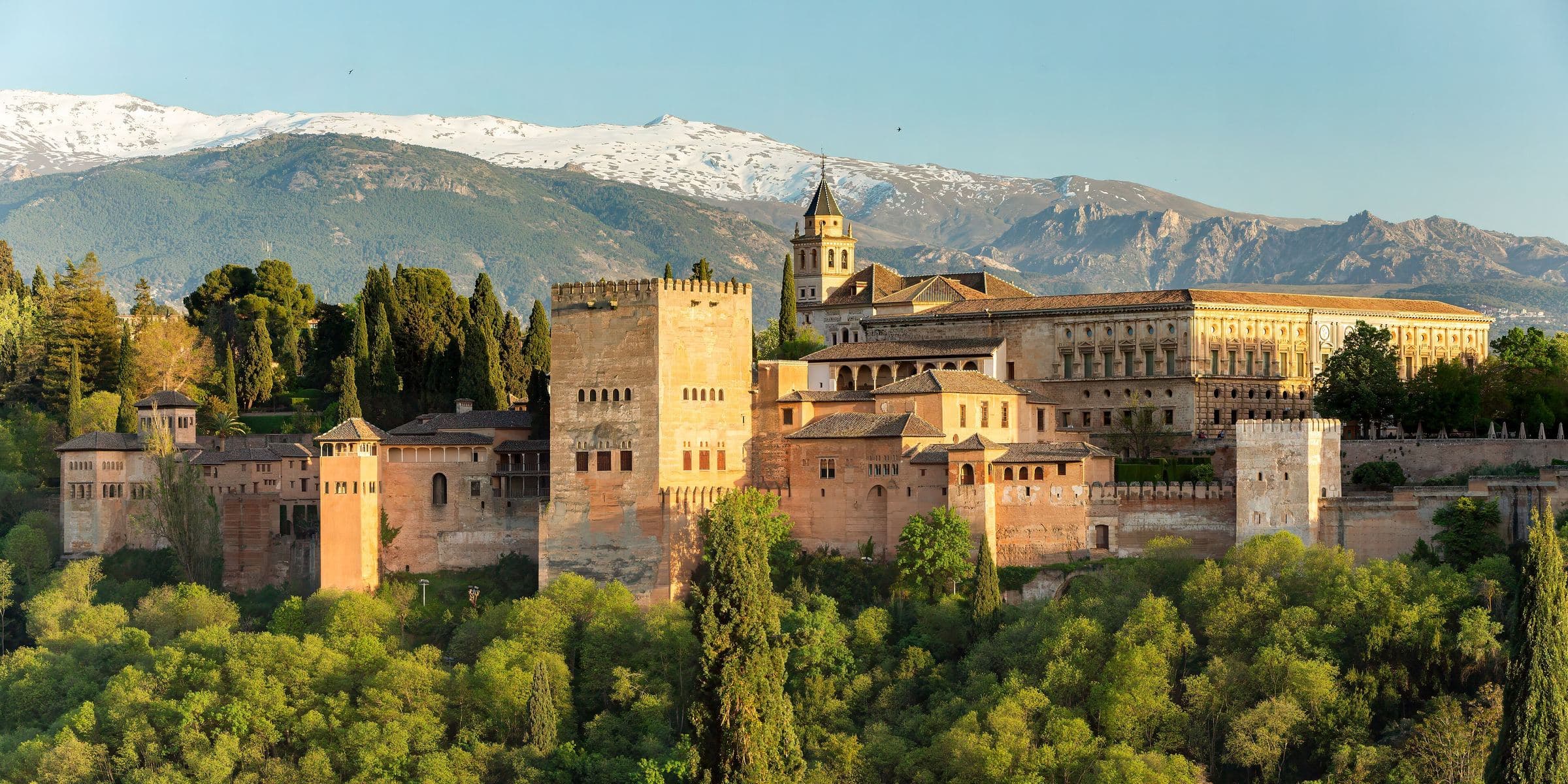 The Alhambra fortress and palaces complex viewed from the Mirador de San Nicolás with Sierra Nevada mountains
