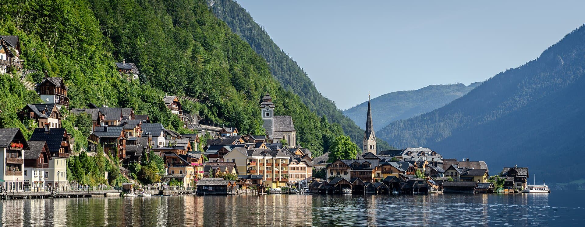 Timber-clad houses of Hallstatt and the Evangelical parish church steeple reflected across Lake Hallstatt