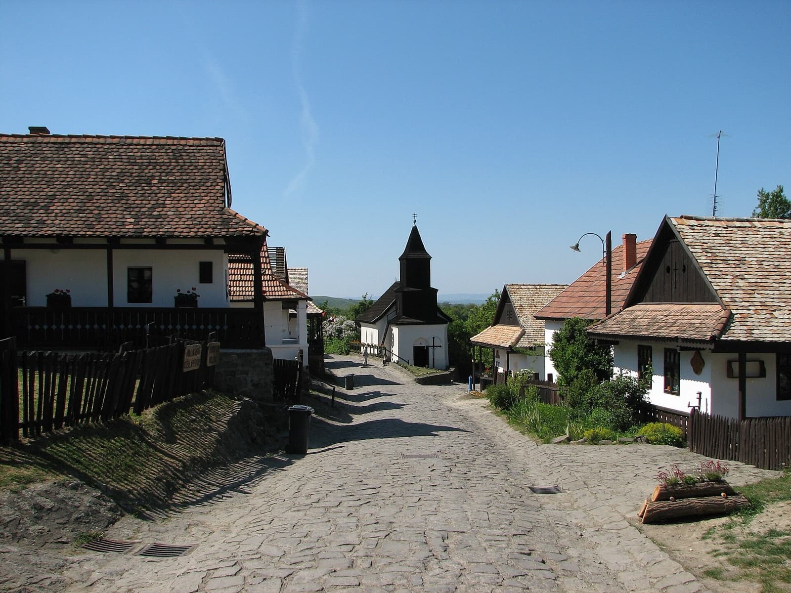 The shingled wooden belfry of Saint Martin Church nestled amongst the whitewashed folk houses of Hollókő