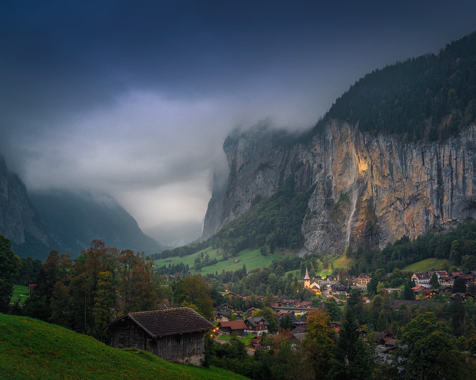 Lauterbrunnen valley with illuminated chalets, waterfalls and towering mountain cliffs