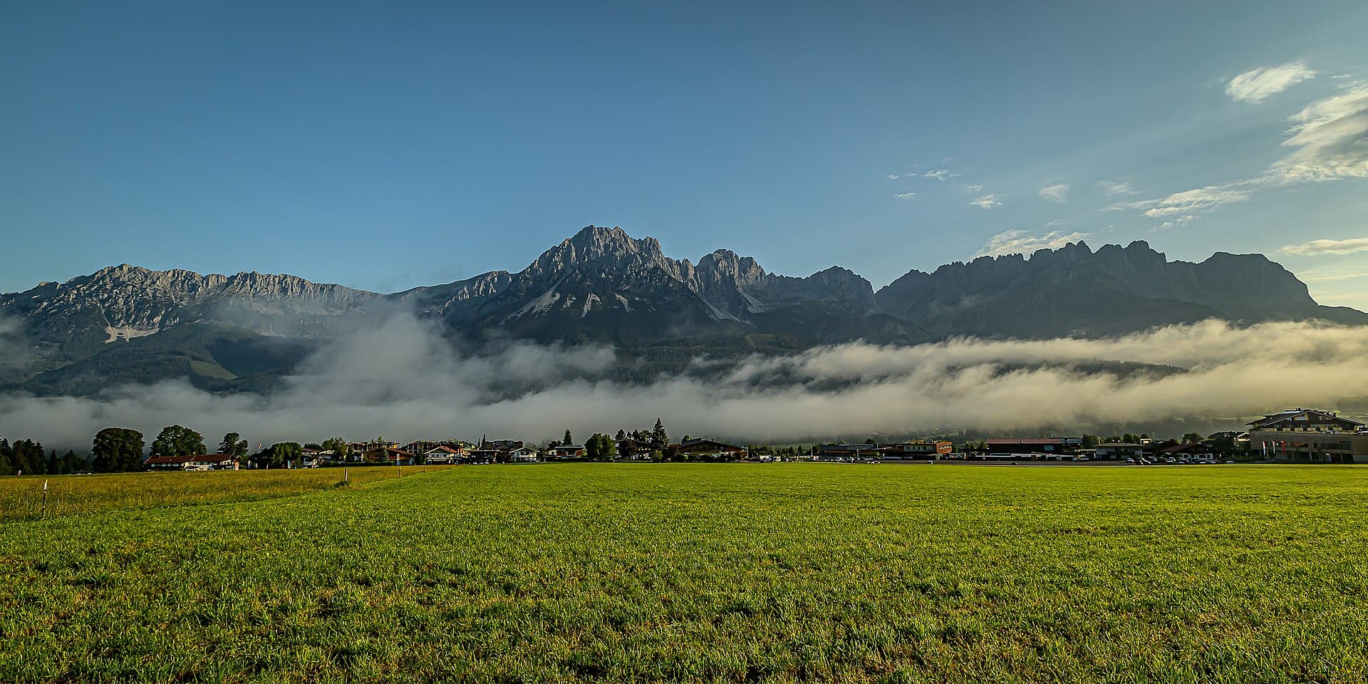 The rugged limestone peaks of the Wilder Kaiser massif towering above green Tyrolean alpine meadows