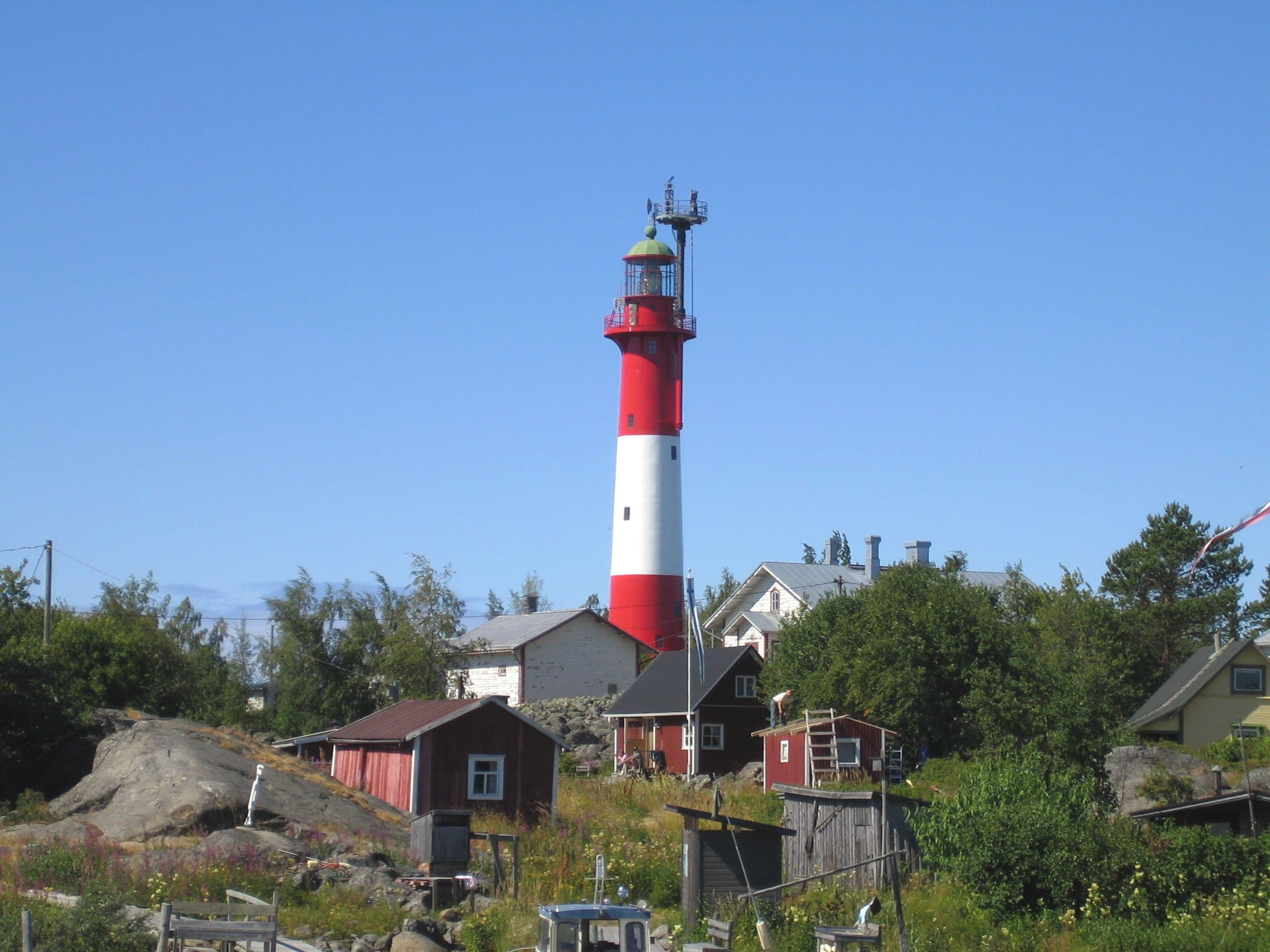 Iconic red-and-white Tankar lighthouse and timber pilot cottages on an isolated rocky island in the Gulf of Bothnia