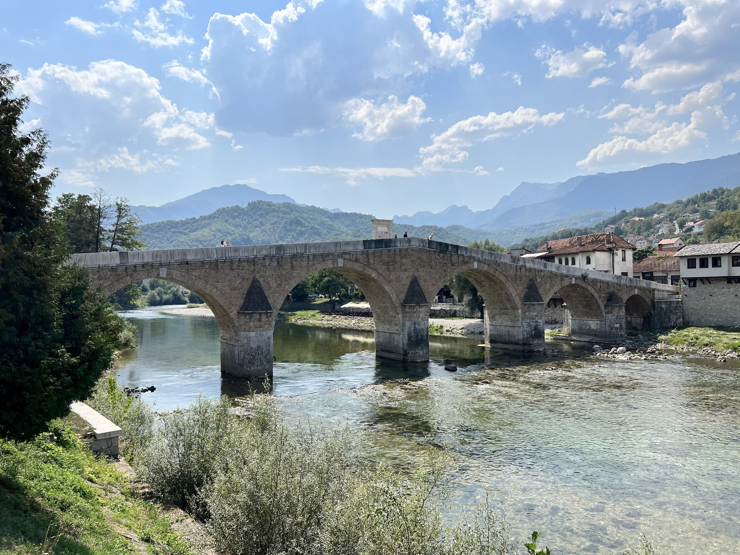 Historic stone arched Stara Ćuprija bridge over the emerald Neretva River in Konjic with mountain backdrop