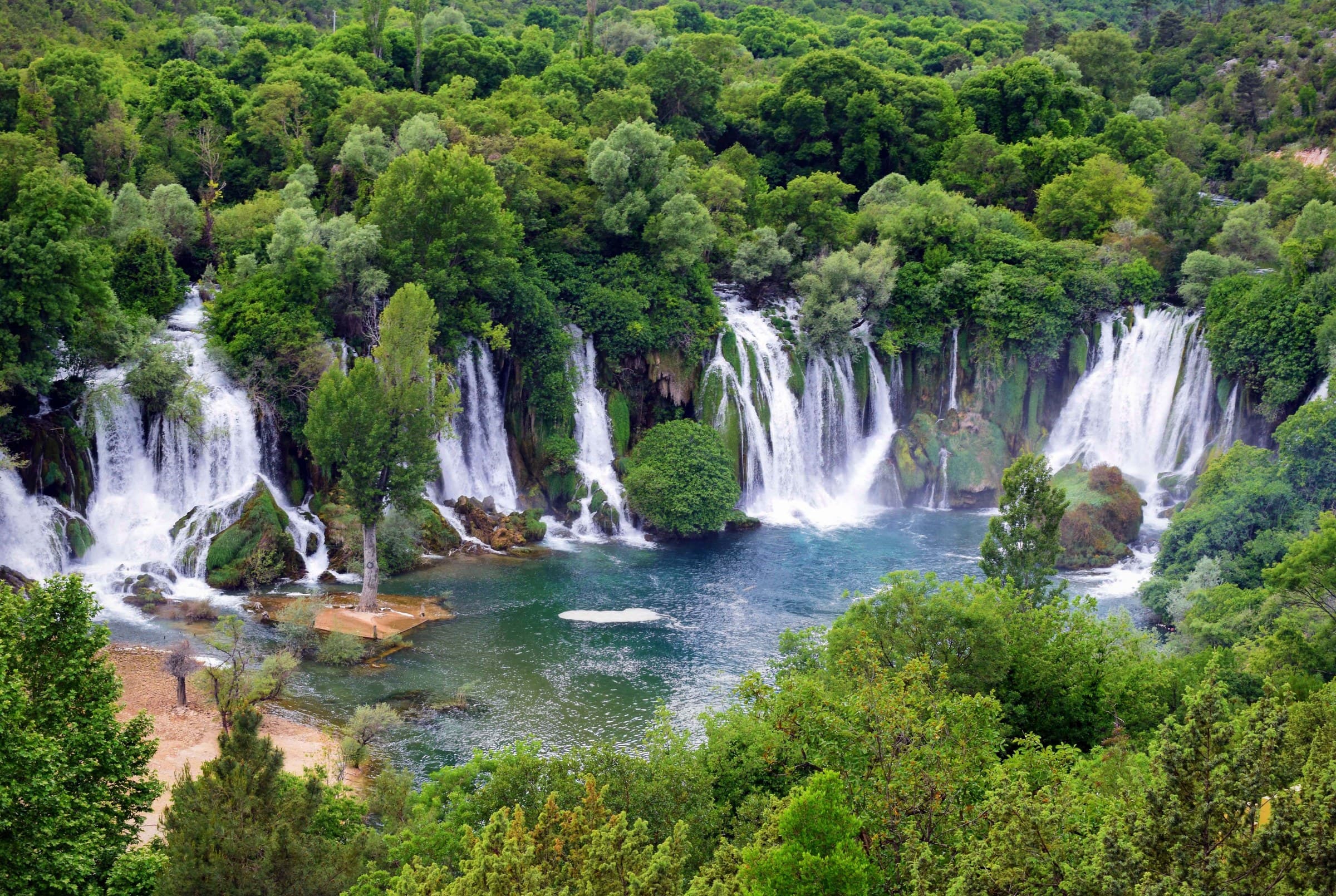Wide natural amphitheatre of roaring Kravica waterfalls cascading into a turquoise natural swimming lagoon