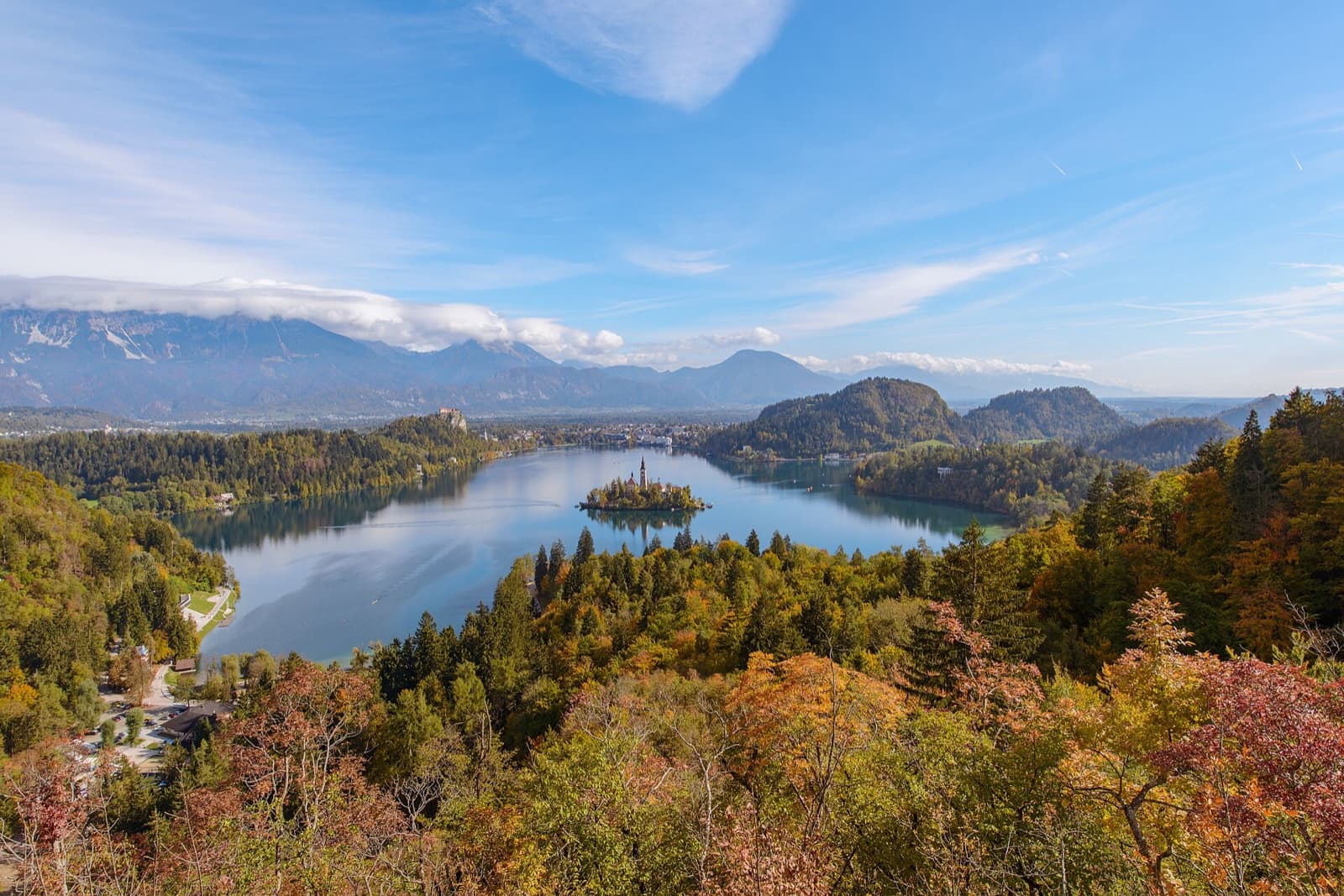 Bled Island church bathed in golden morning light amidst the emerald waters of Lake Bled with the Julian Alps beyond