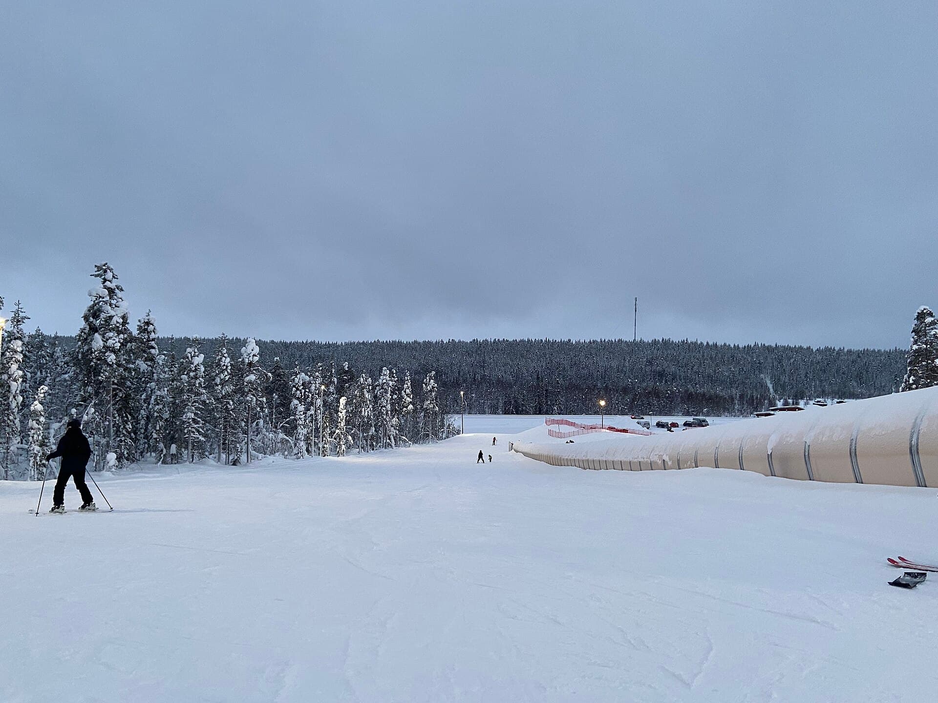 Snow-covered pine forests and illuminated ski slopes of Levitunturi fell in Lapland under winter skies
