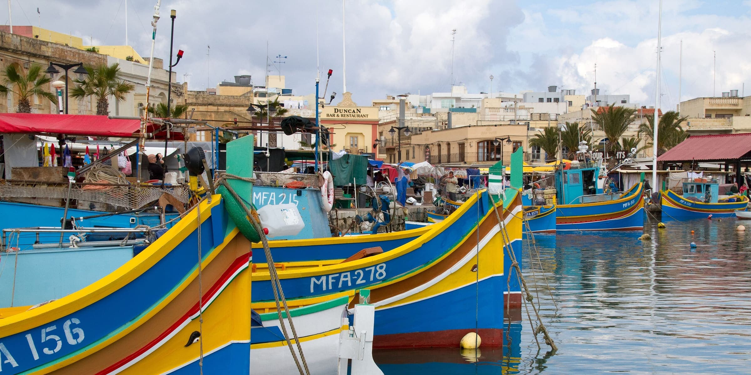 Brightly painted luzzu fishing boats moored in Marsaxlokk harbour