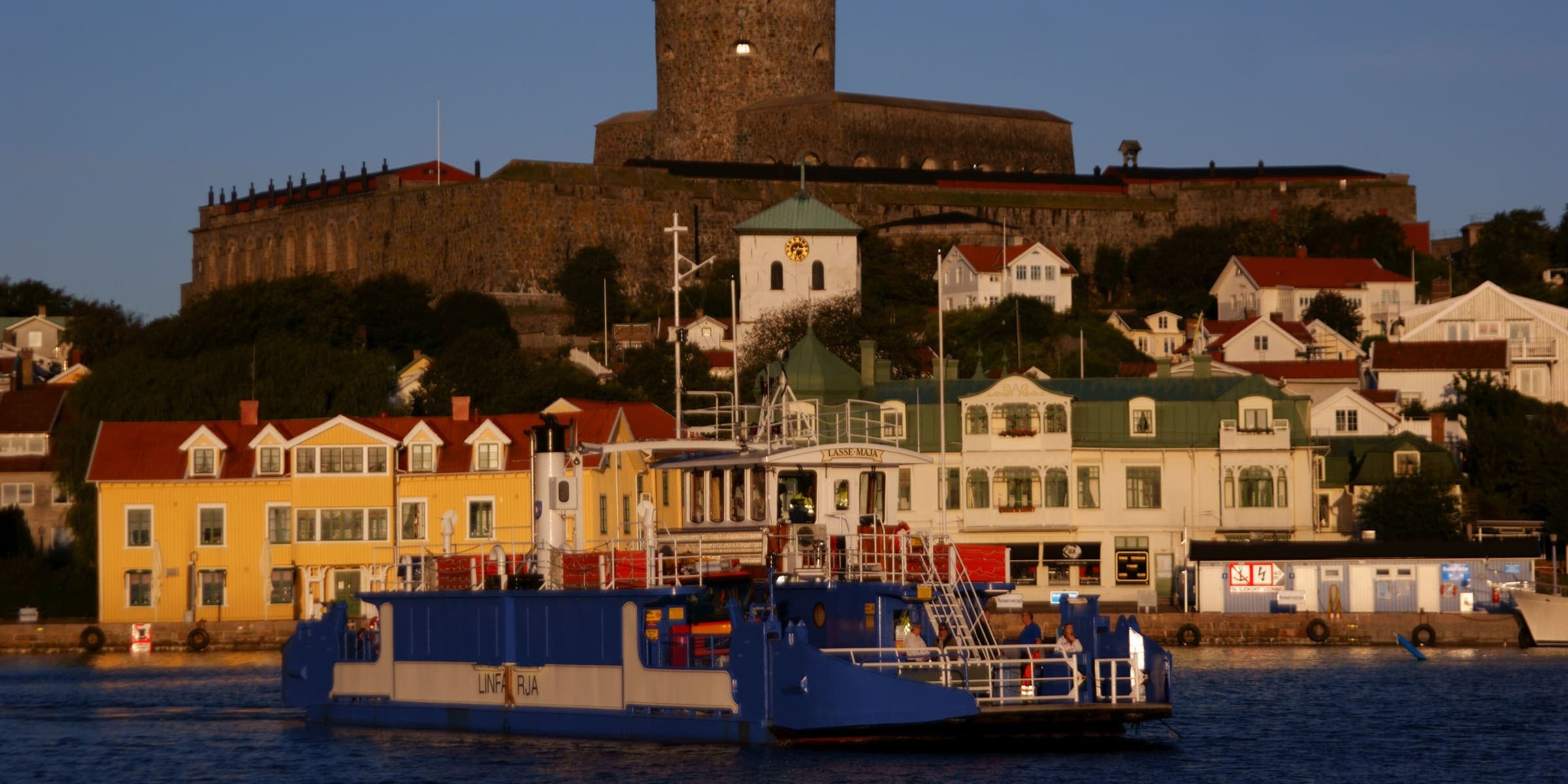 Carlsten Fortress above Marstrand's harbour and painted houses, with the ferry crossing