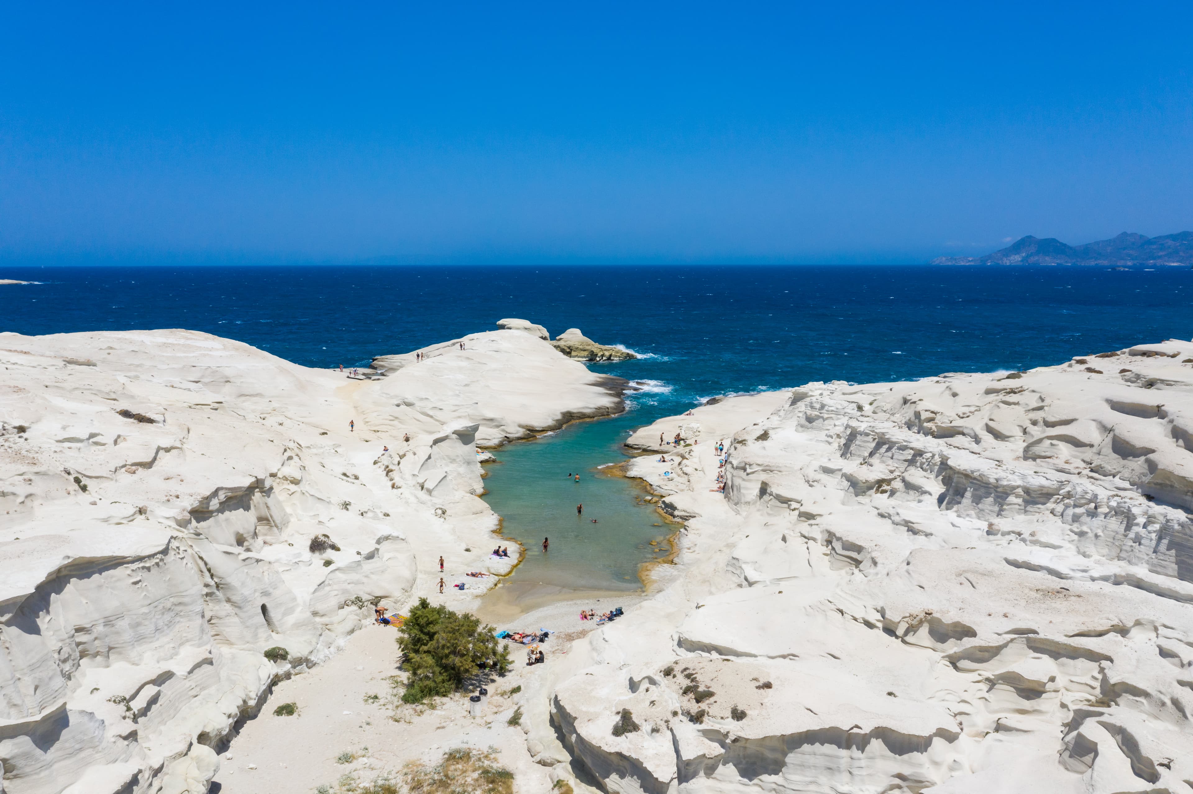 Sculpted white volcanic rock formations framing turquoise inlets at Sarakiniko on Milos