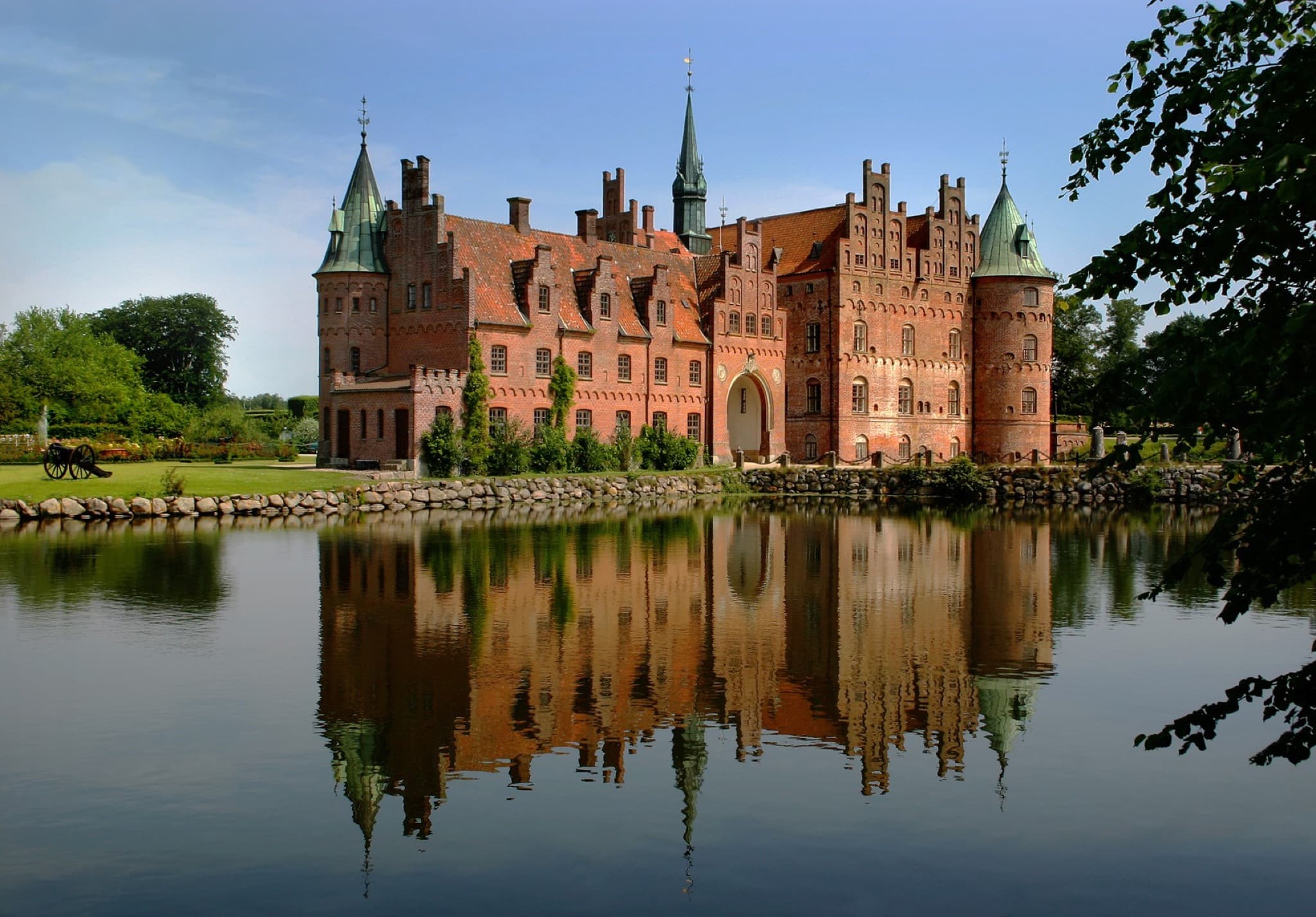 Egeskov Castle moat and Renaissance spires reflecting in the water on Funen