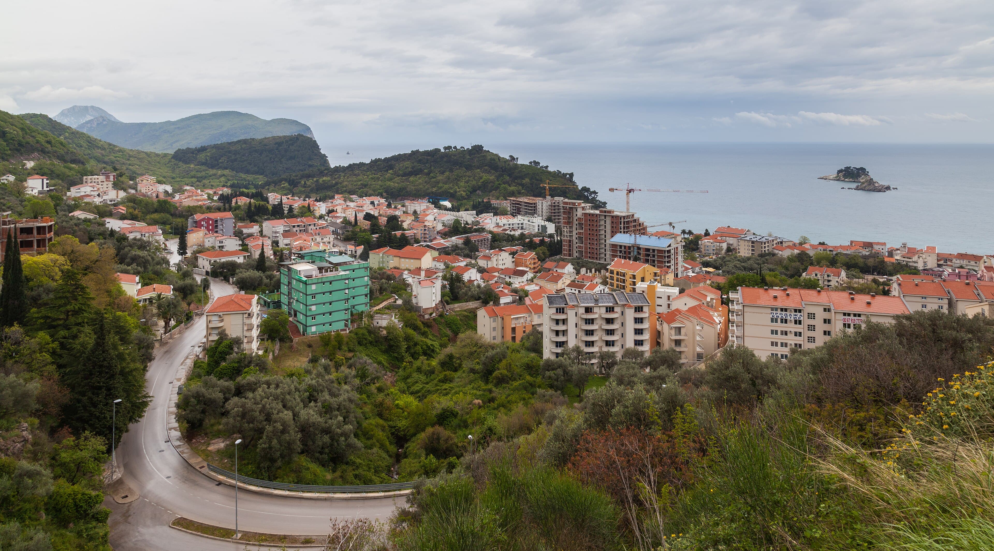 The red-pebble bay of Petrovac with the stone Kastio fortress on the headland and two islets offshore