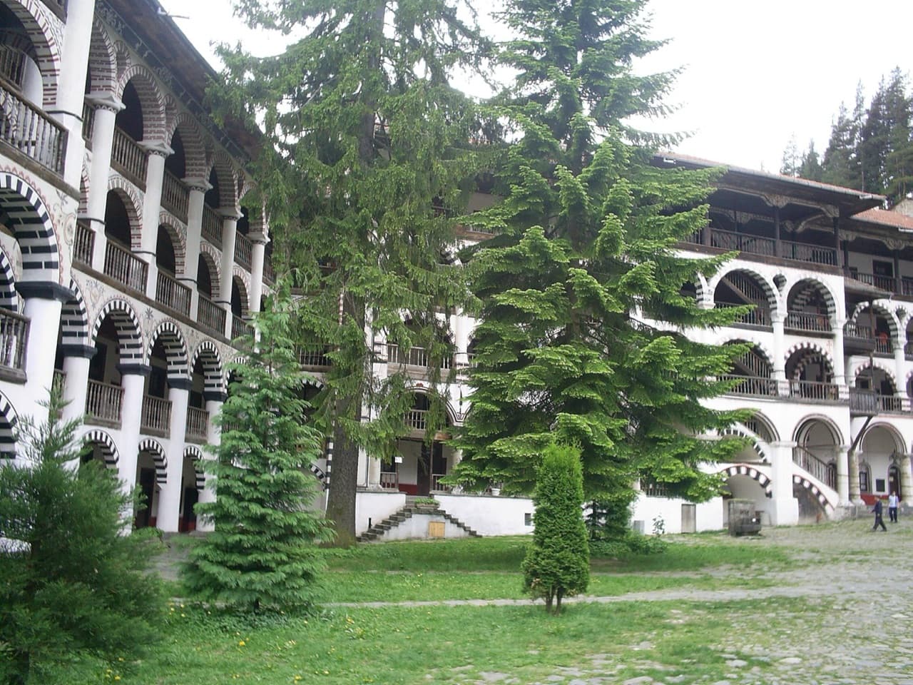 The striking striped arcades, timber balconies, and central church in the inner courtyard of Rila Monastery