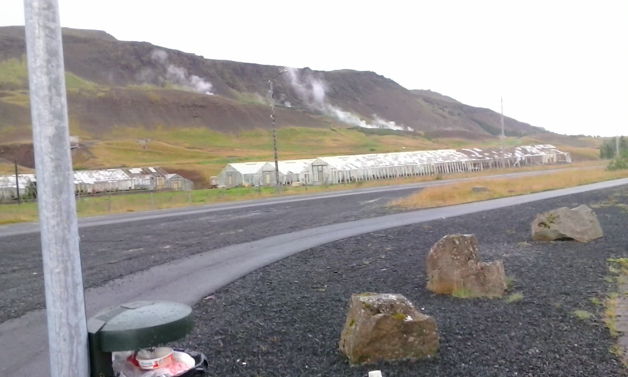 Steaming geothermal steam vents and greenhouses nestled in the green valley hills of Hveragerði