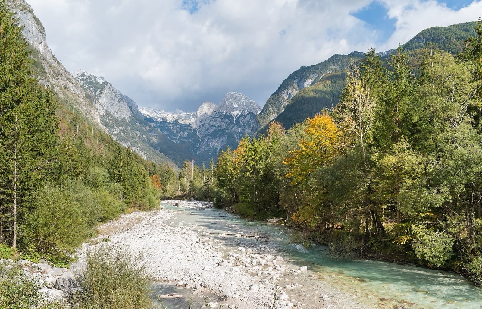The astonishing emerald-turquoise waters of the Soča River flowing over polished limestone boulders beneath the Julian Alps