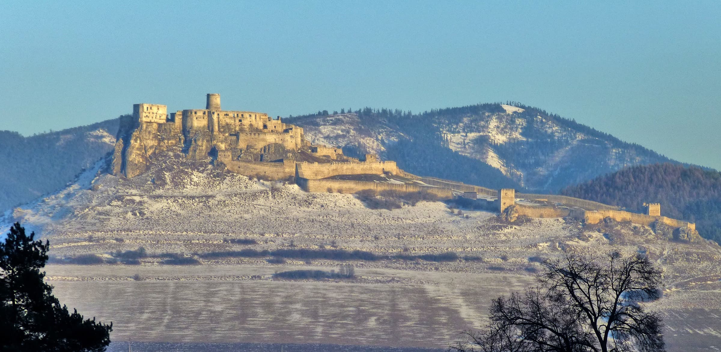 The vast white limestone ruins of Spiš Castle standing proudly atop a green travertine hill