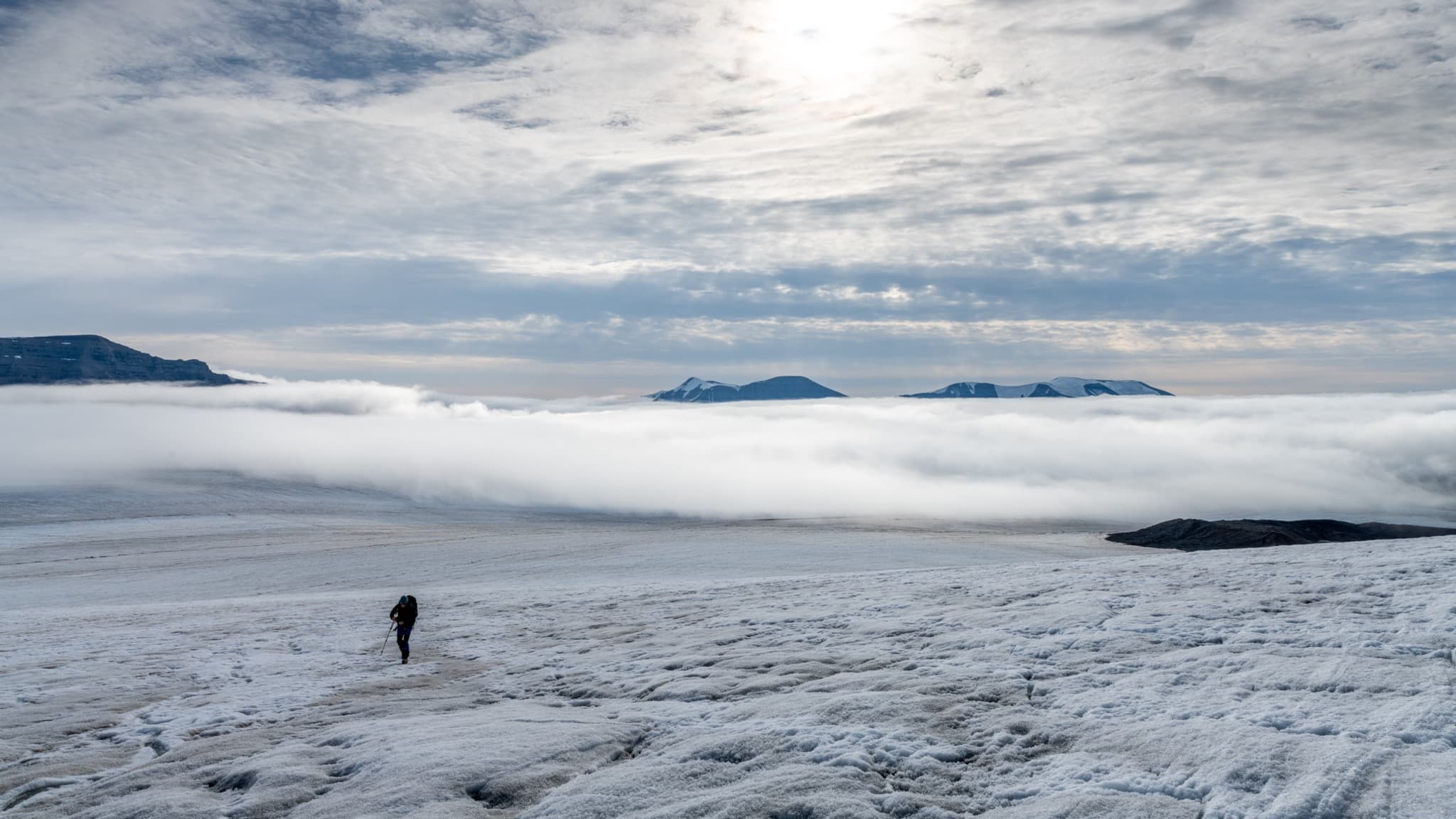 Vast Arctic wilderness of Svalbard with snow-covered tundra mountains and blue glacier ice under pale polar skies
