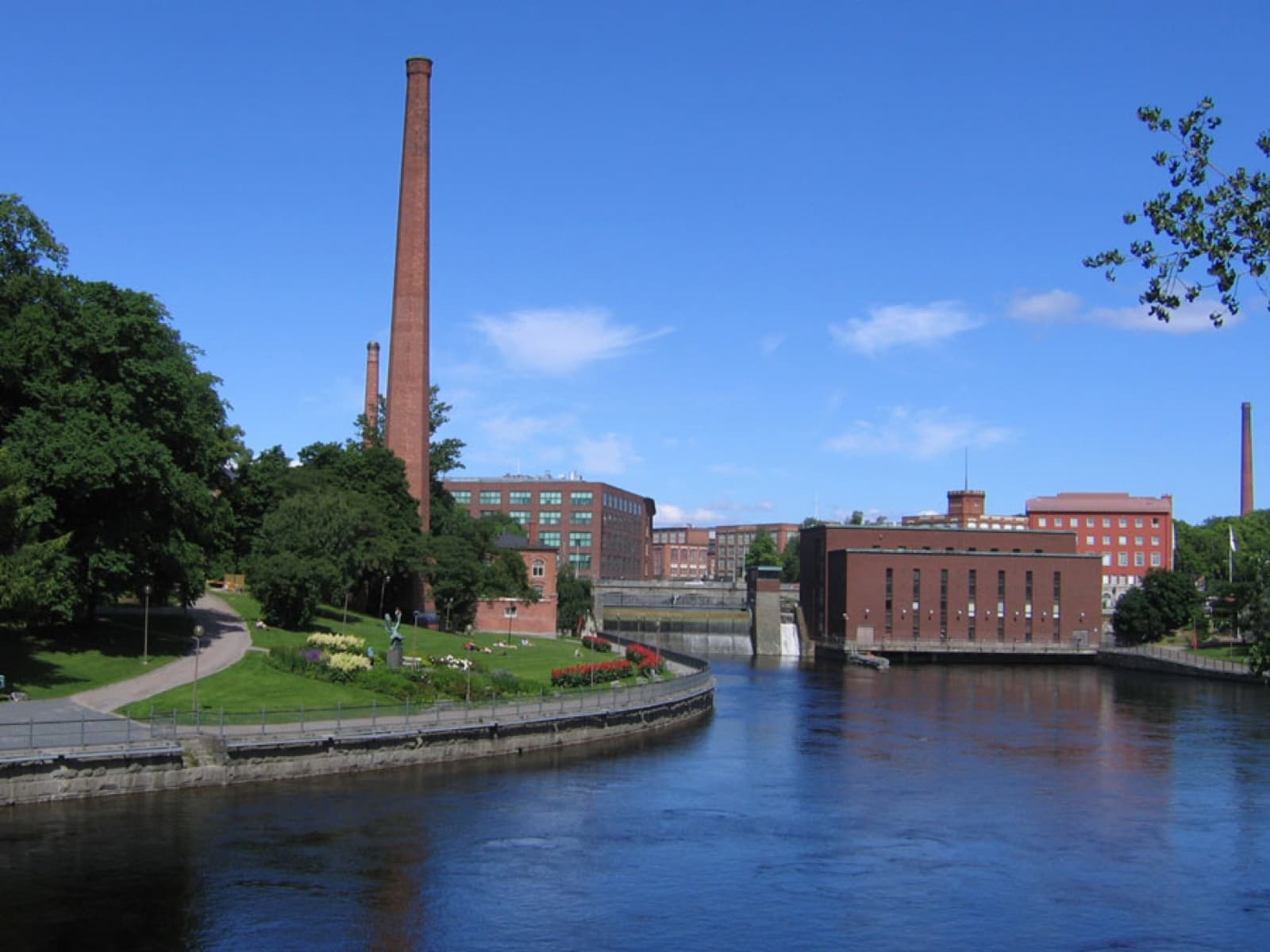The rushing foam of the Tammerkoski rapids coursing past the illuminated red-brick industrial cotton mills in Tampere