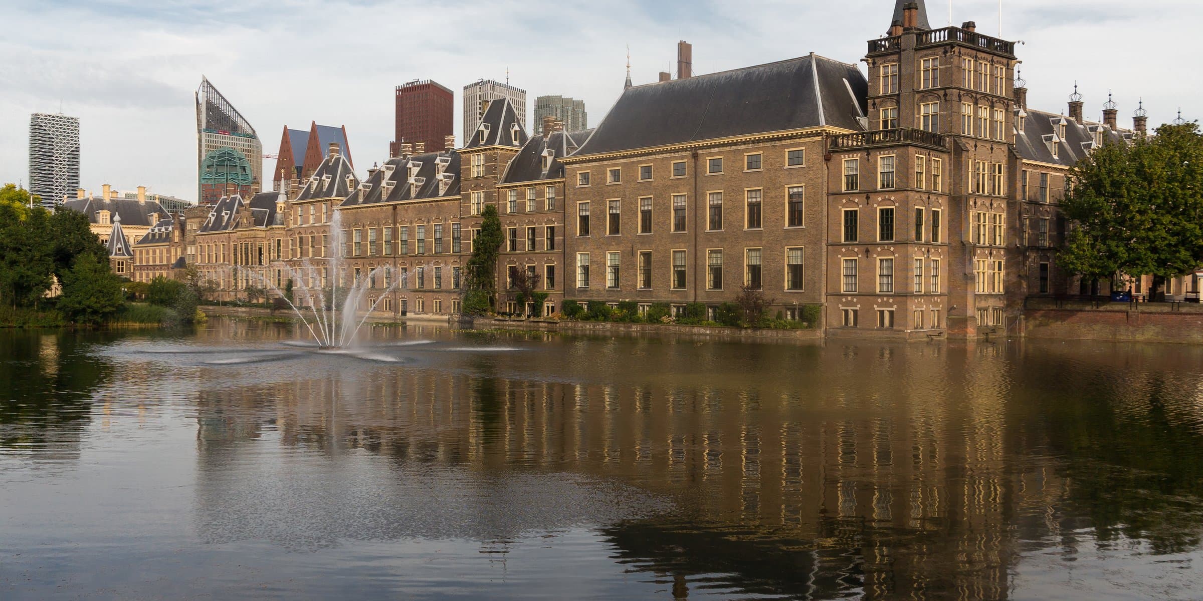 The historic Binnenhof parliament buildings reflected across the Hofvijver lake in The Hague