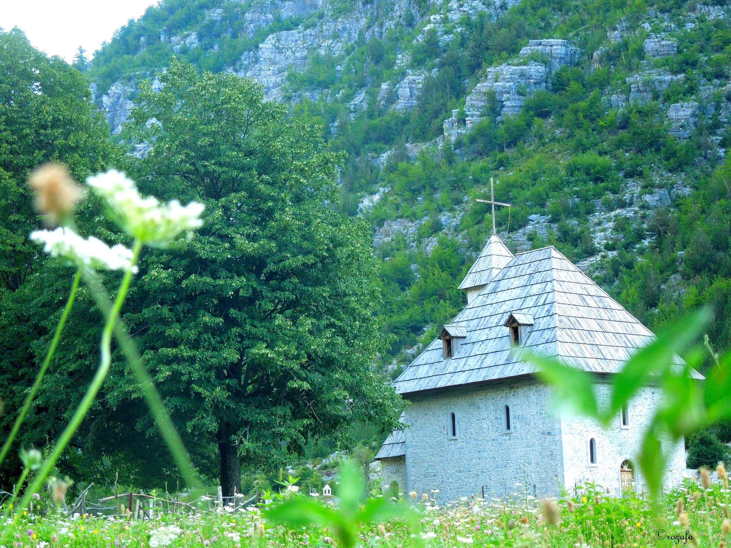 The iconic stone Catholic church of Theth framed by jagged limestone peaks in the Accursed Mountains