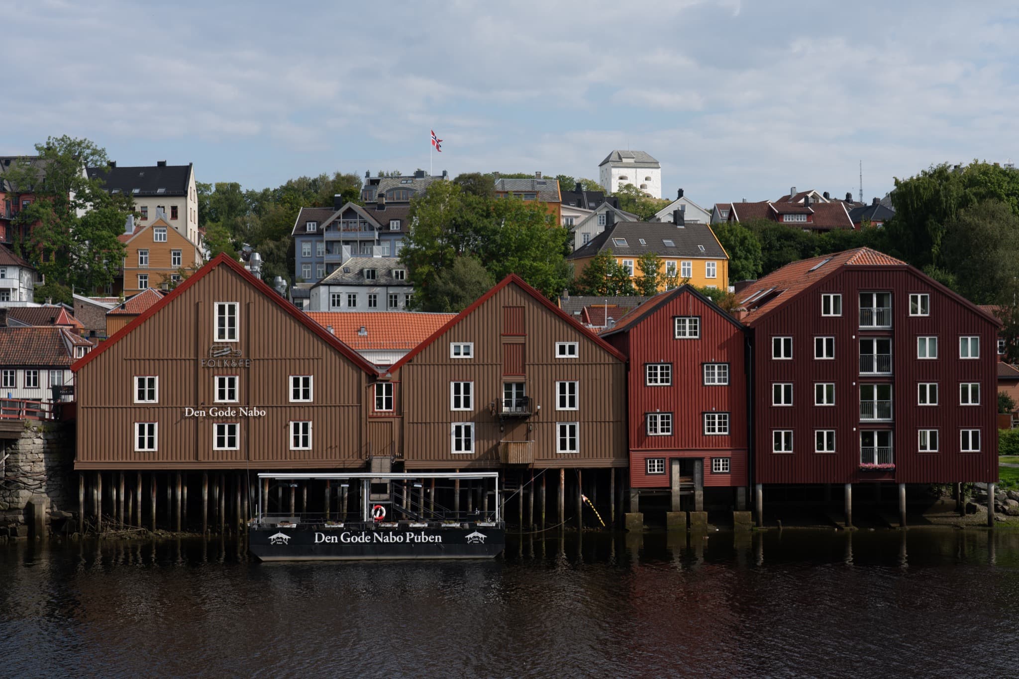 Colourful historic timber wharves reflecting in the calm waters of the river Nidelva in Trondheim