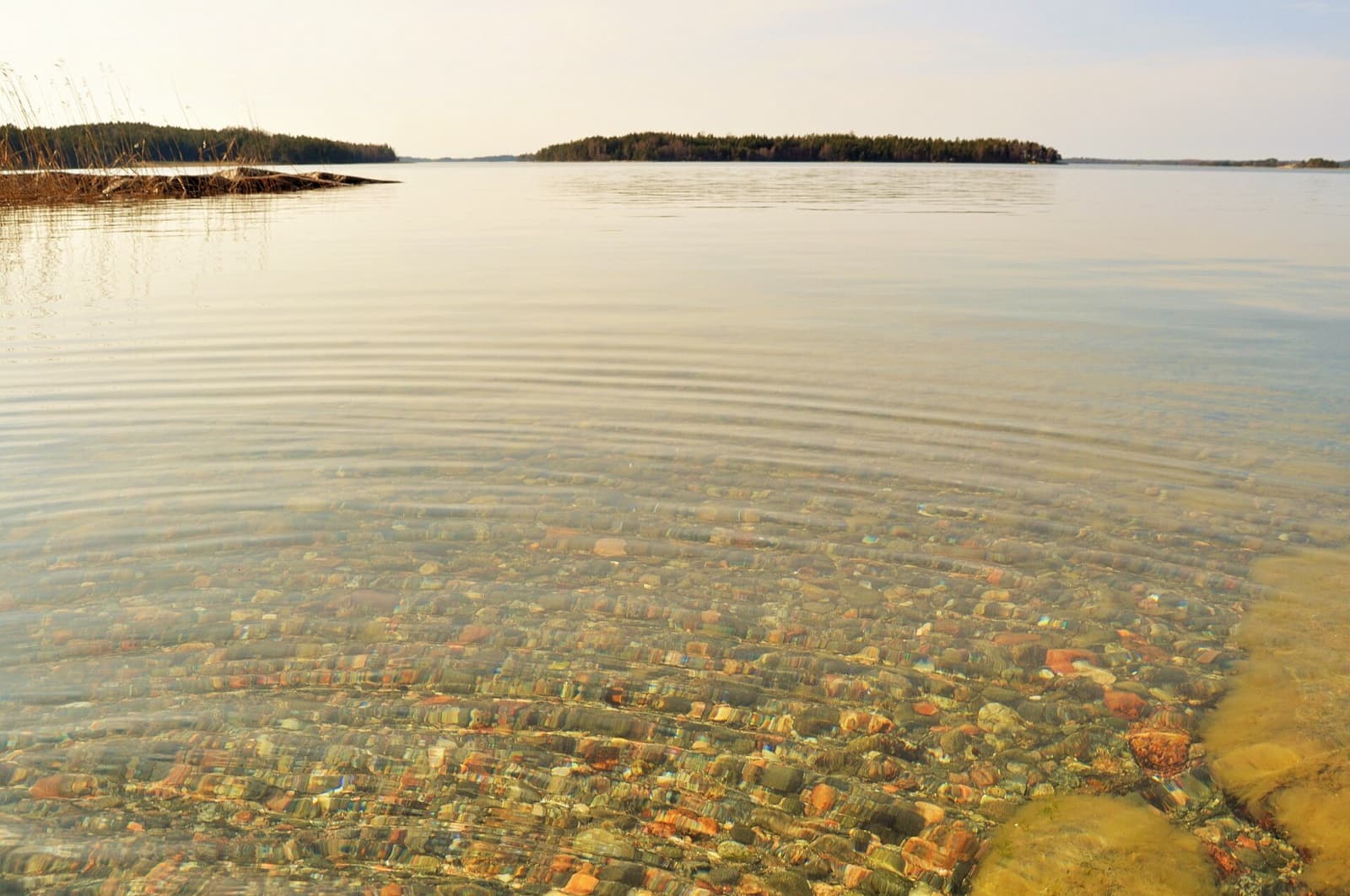 A classic yellow car ferry crossing shimmering blue waters between pine-covered granite islands in the Turku Archipelago
