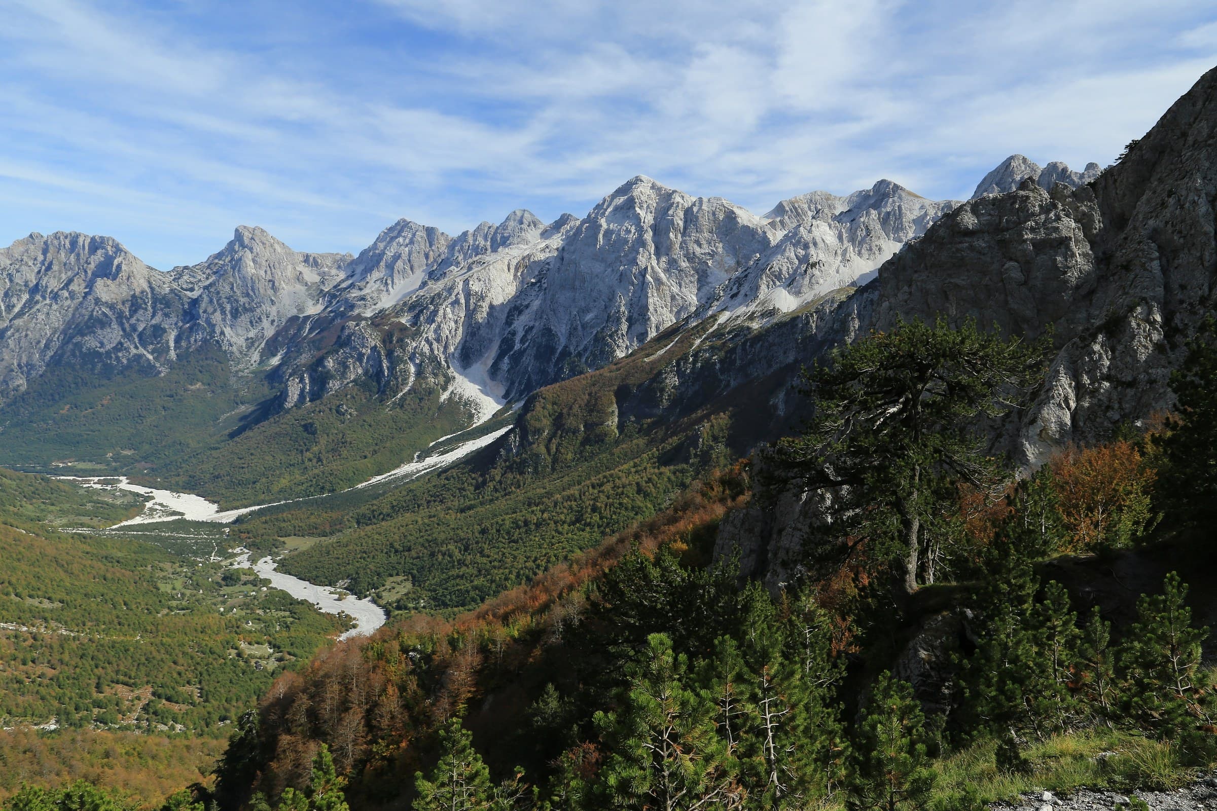 Glacial gravels and emerald waters of the Valbona River surrounded by towering beech forests and limestone peaks