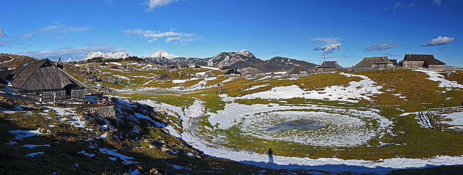 The distinctive oval spruce-shingle herdsmen's huts dotting the green alpine meadows of Velika Planina beneath the Kamnik-Savinja Alps