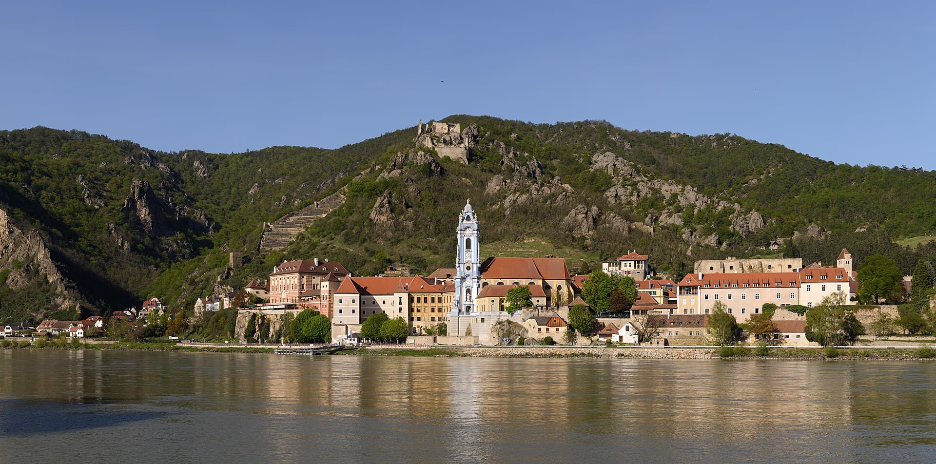 Terraced vineyards and the blue baroque church tower of Dürnstein overlooking the Danube river in the Wachau