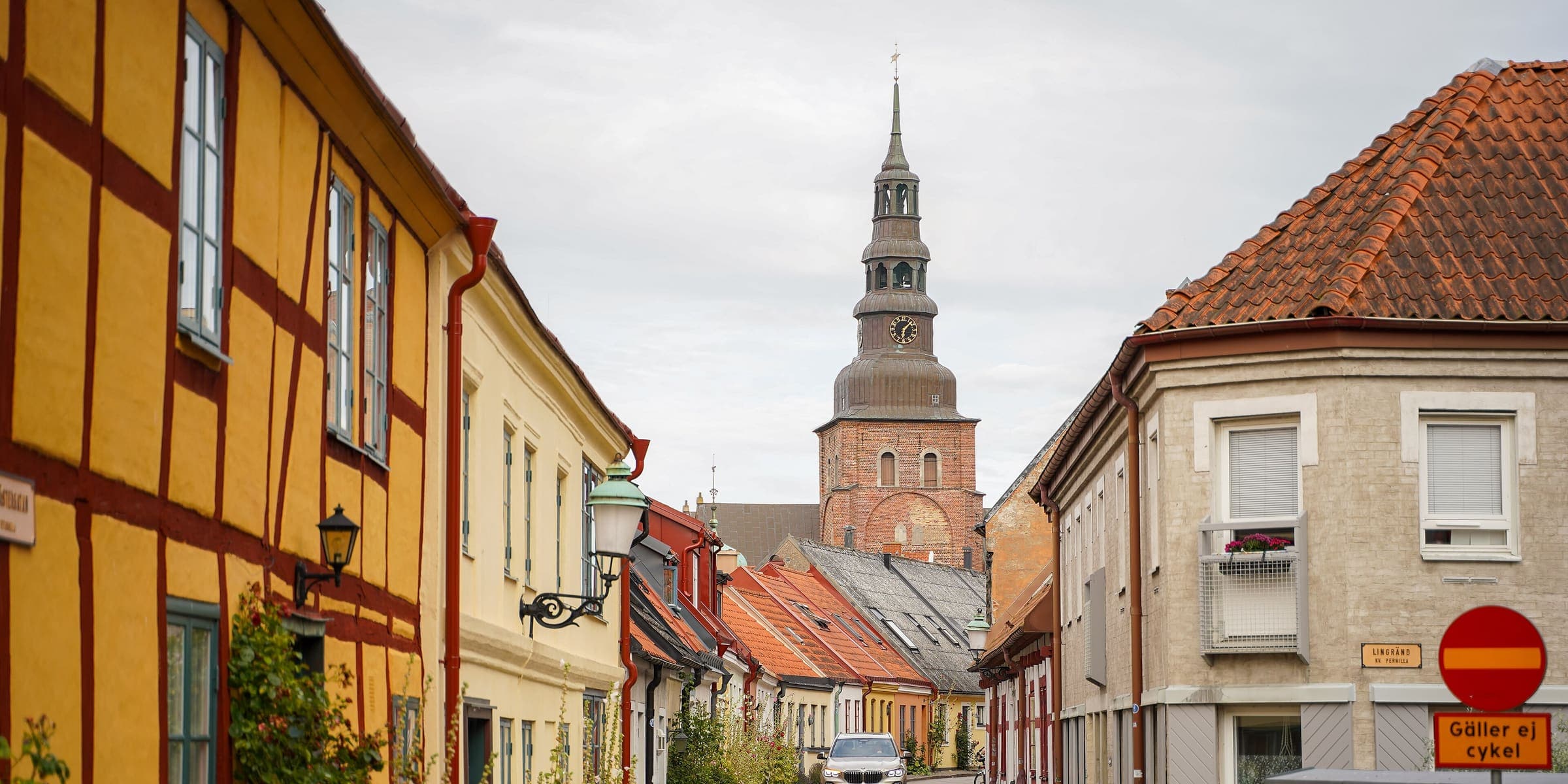 A lane of half-timbered houses in Ystad with St Mary's church tower behind