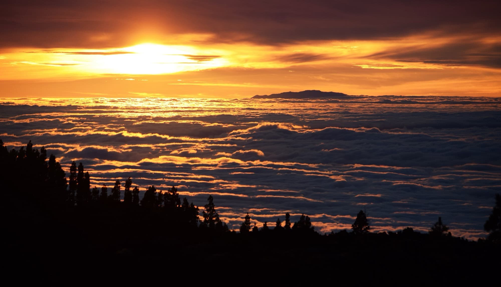 Golden sunset over the volcanic ridge and ocean clouds viewed from Mount Teide