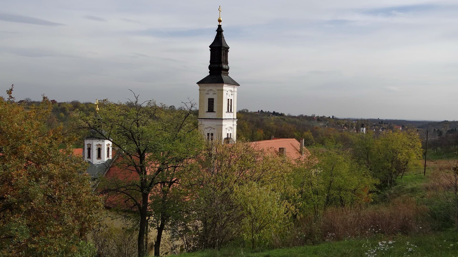 Bell tower and courtyard of an Orthodox monastery among the beech woods of Fruška Gora