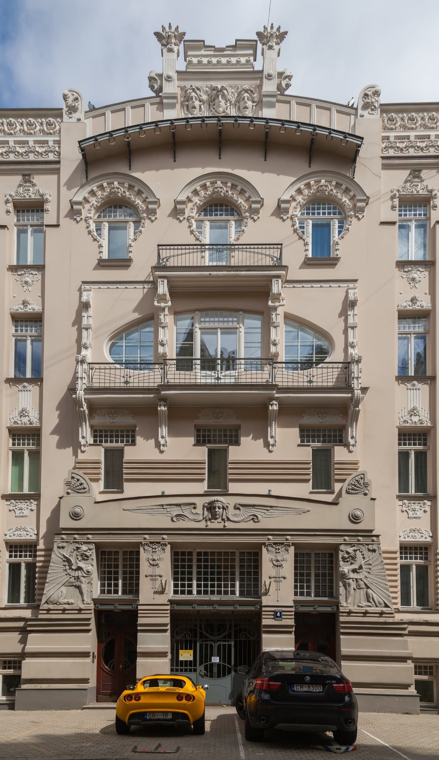 Intricately sculpted Art Nouveau facade with carved masks and statues on Alberta iela in Riga