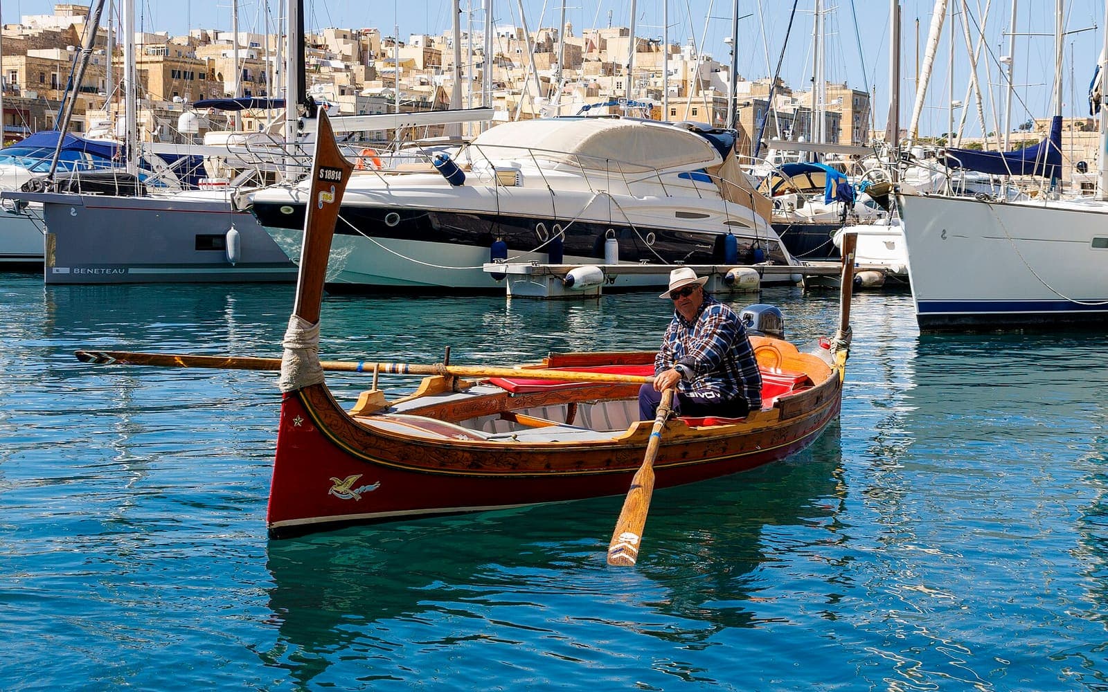 A traditional painted dgħajsa being rowed in a Maltese harbour