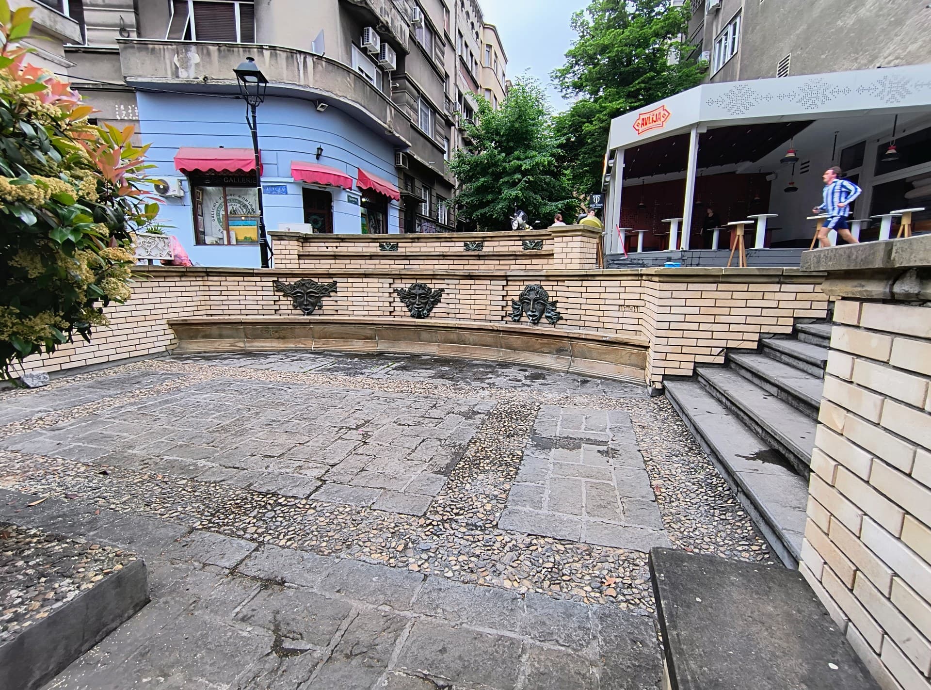 Lantern-lit cobbled terrace of a Skadarlija kafana set with tables under the trees in Belgrade