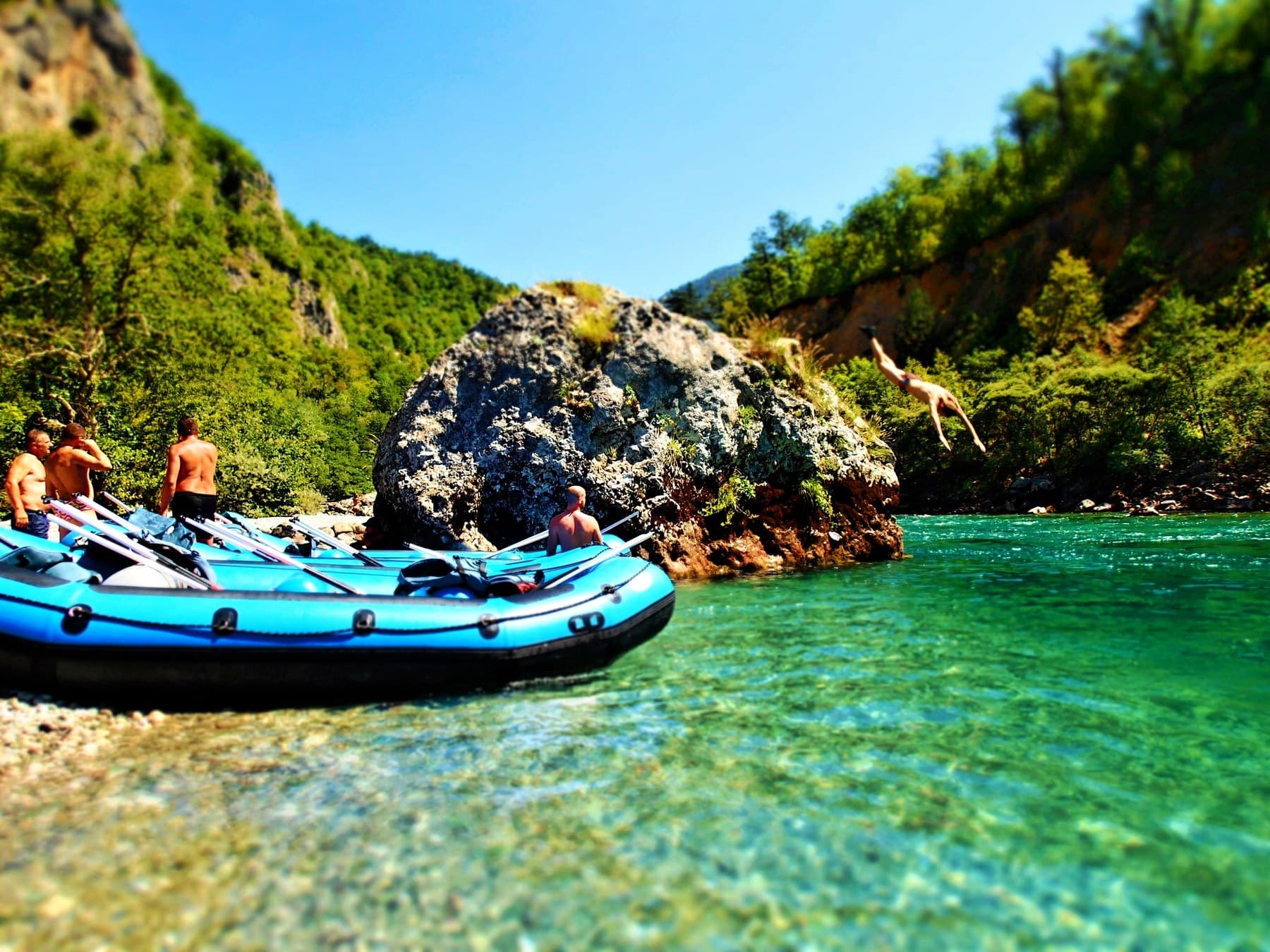 Inflatable raft navigating turquoise rapids through the steep wooded walls of the Tara River Canyon