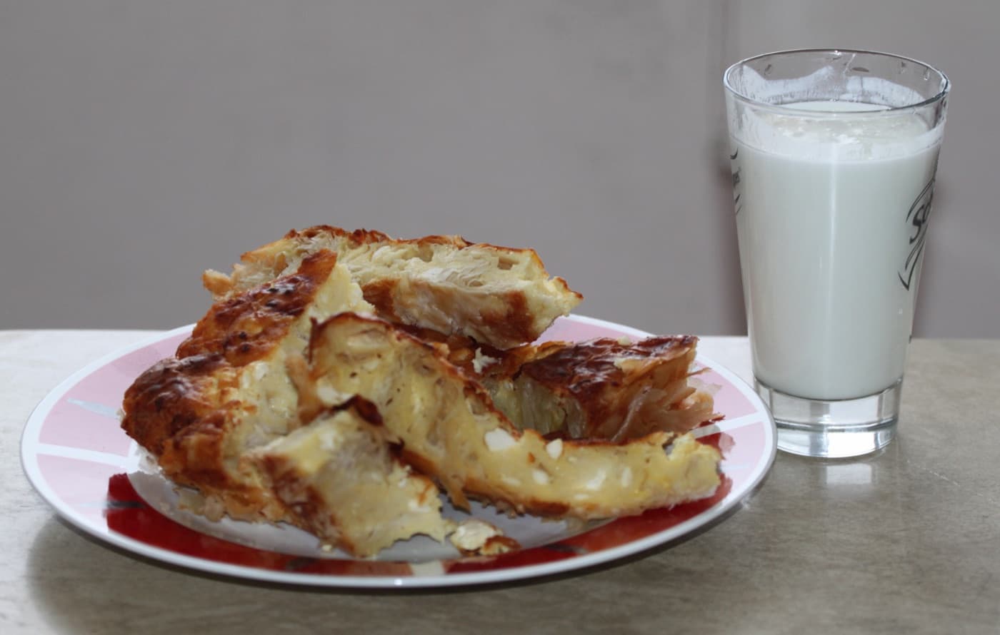 Golden spiralled Bulgarian banitsa filo pastry fresh from the oven cut into portions